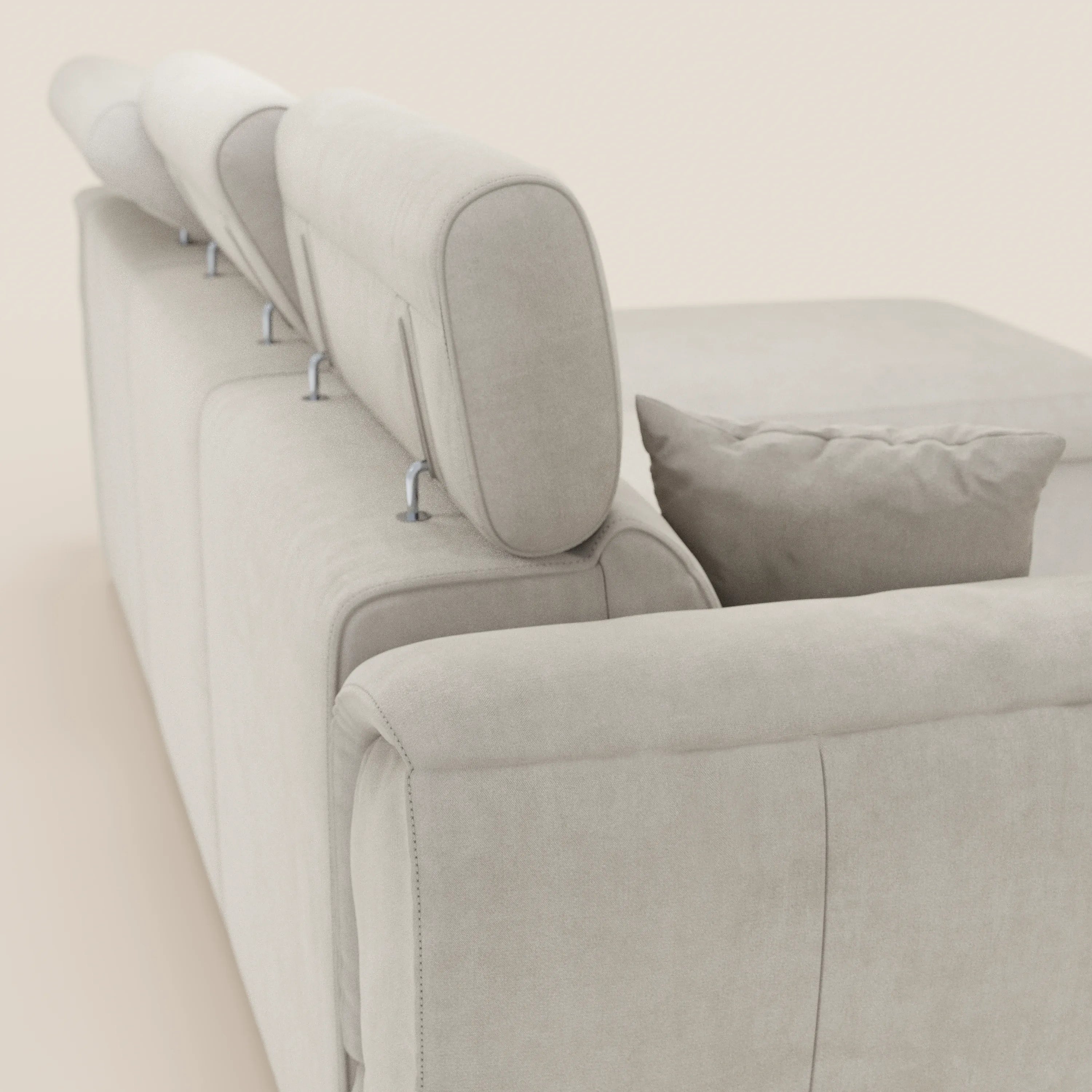 Un primo piano del divano letto Titano con penisola reversibile di Divani.Store, in tessuto smacchiabile beige chiaro, con poggiatesta reclinabili, contenitore, elemento estraibile e un cuscino coordinato: linee moderne su uno sfondo neutro.