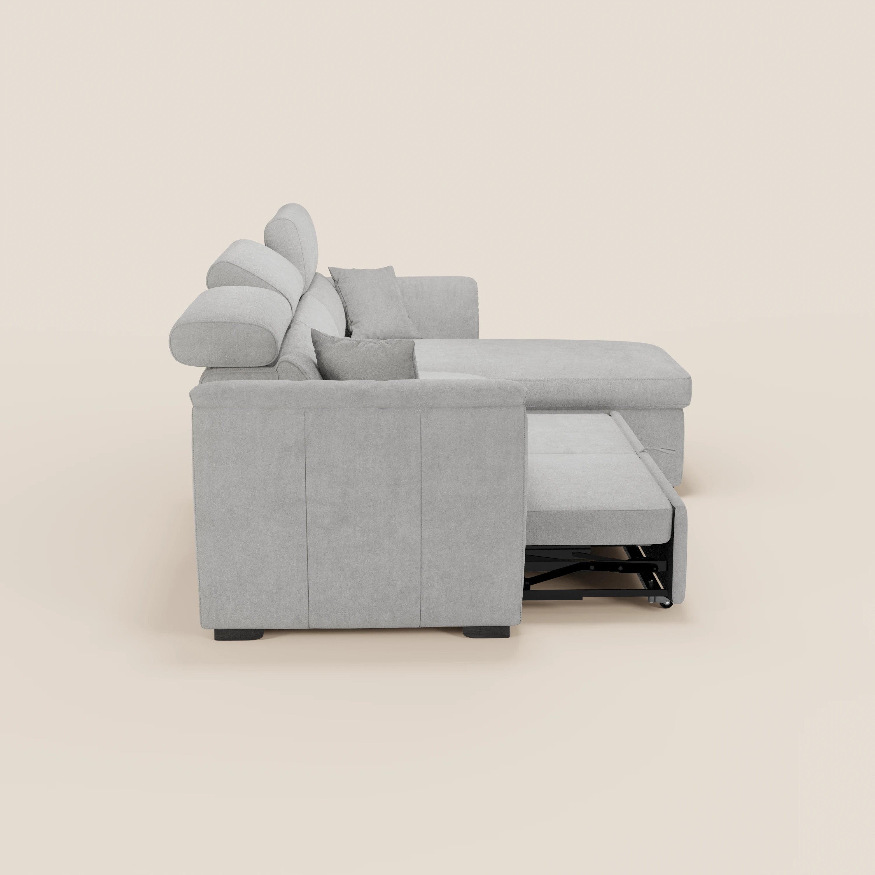 Il divano letto Titano di Divani.Store è un divano in tessuto grigio chiaro antimacchia, dotato di chaise longue reversibile, poggiatesta regolabili, braccioli squadrati, due cuscini dello schienale e una parte letto estensibile. Sfondo beige a tinta unita.