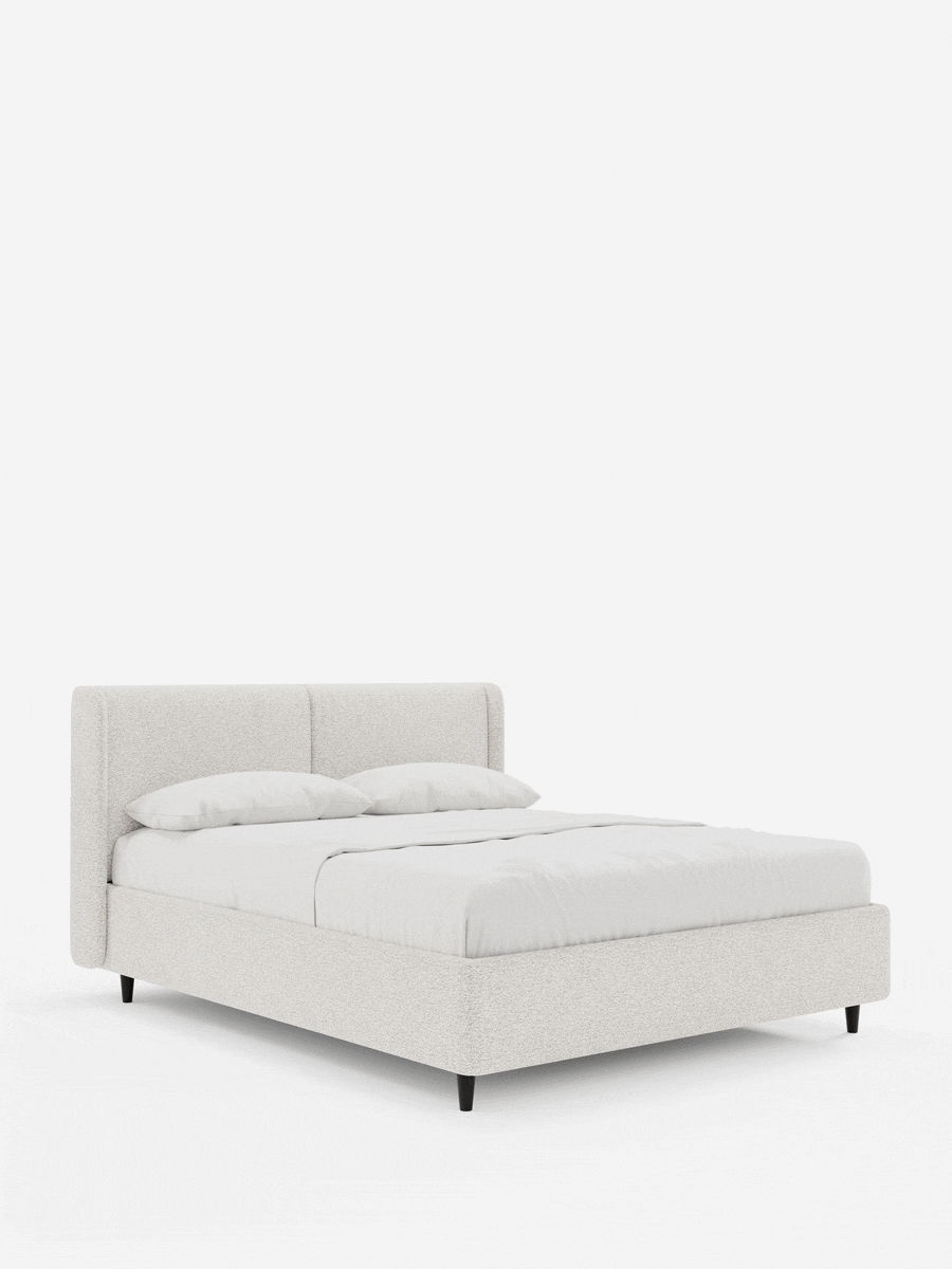 VALKIRIA, letto di design con contenitore e testiera avvolgente, rivestito in beige chiaro con due morbidi cuscini, tessuto a trama, lenzuola bianche immacolate e gambe affusolate scure su sfondo bianco.