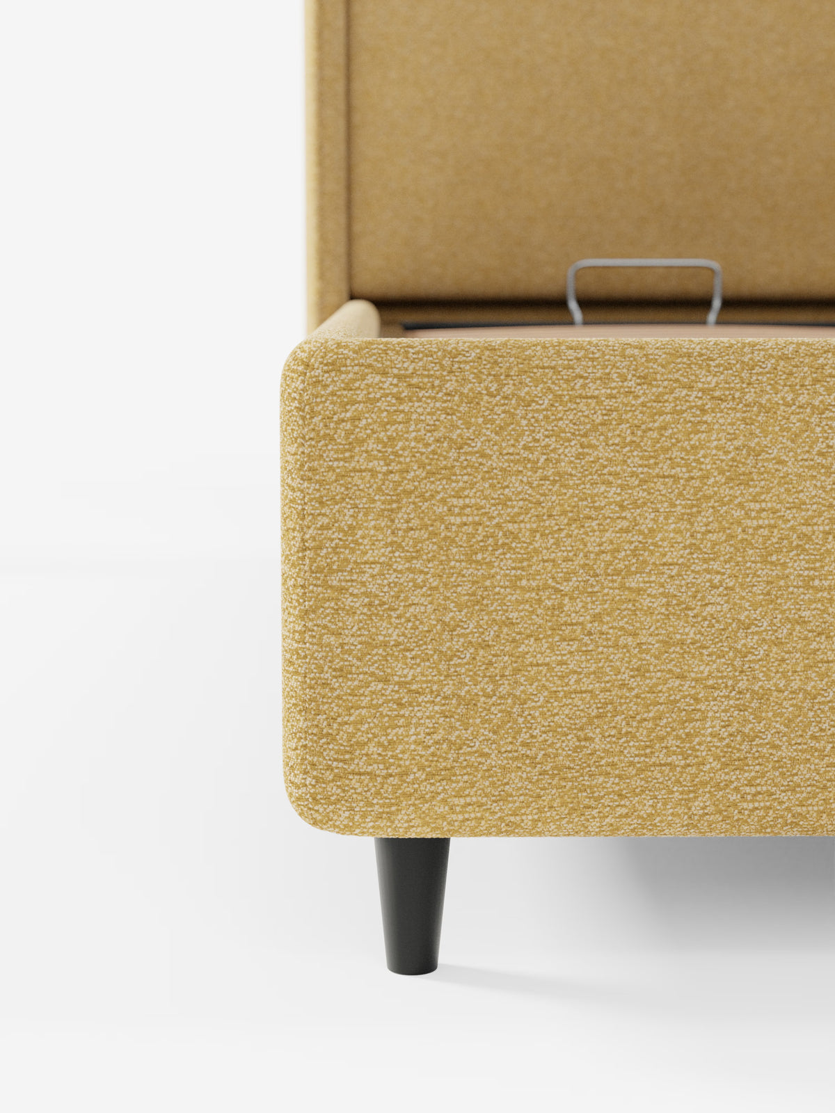 Primo piano del letto di design VALKIRIA di Letti.store, caratterizzato da un tessuto testurizzato giallo senape certificato Oeko-Tex®, gambe affusolate in legno nero e una maniglia in metallo a vista sul vano portaoggetti interno. La testiera avvolgente con due cuscini imbottiti risalta sullo sfondo bianco: un’elegante espressione del design contemporaneo per interni moderni.