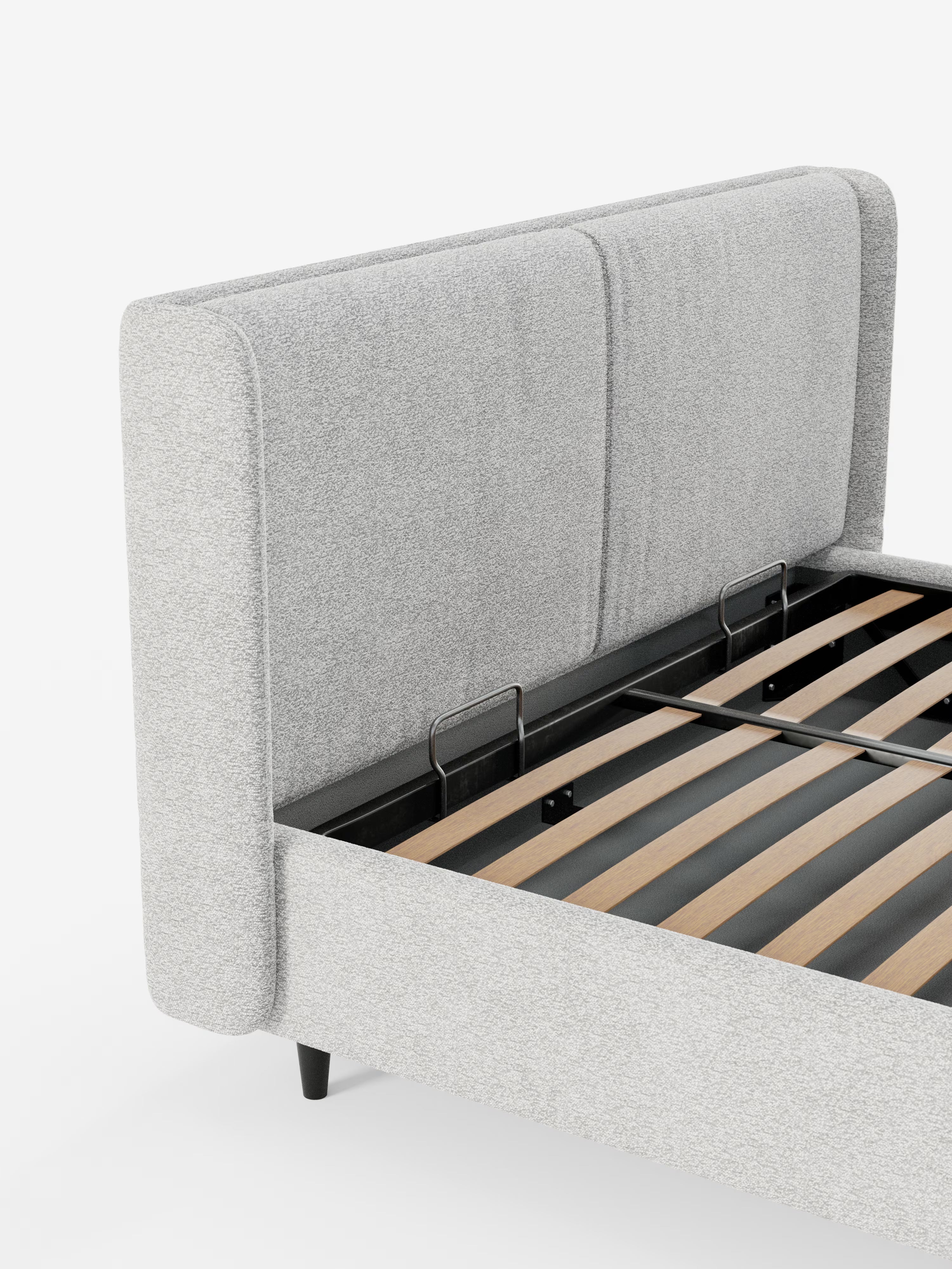 Un primo piano del letto di design VALKIRIA con vano contenitore e testiera avvolgente di Letti.store ne mette in risalto il rivestimento in tessuto grigio chiaro certificato Oeko-Tex® e i due cuscini imbottiti sulla testiera. Sono visibili la robusta struttura in metallo nero e le doghe in legno che sostengono il materasso, con brevi piedini neri che accentuano gli angoli del letto. Sullo sfondo bianco, l’aspetto complessivo ne sottolinea il design contemporaneo e la pratica soluzione di contenimento