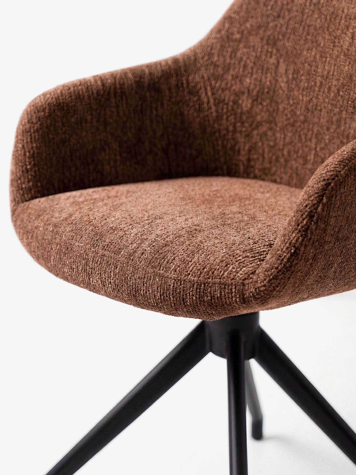 Primo piano della sedia imbottita Vico di Divani.Store, realizzata in morbido tessuto soft-touch certificato OEKO-TEX®, con braccioli ricurvi, seduta imbottita e gambe in metallo nero. Il suo design contemporaneo risalta sullo sfondo bianco a tinta unita.