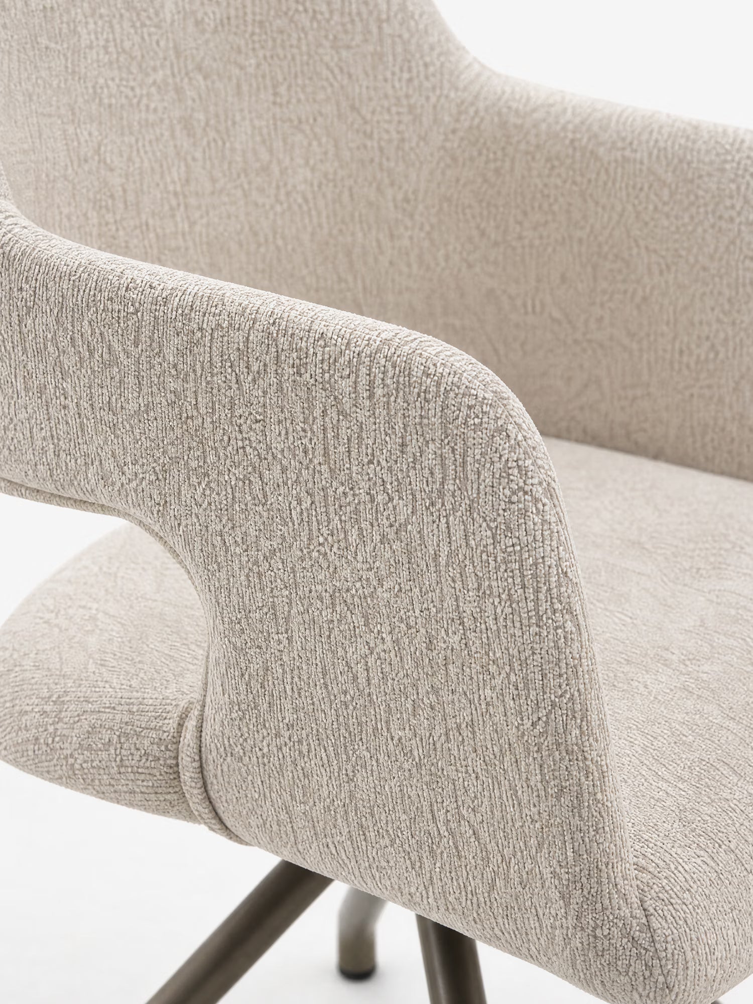 Primo piano della sedia di design Zefira Sedia imbottita con braccioli di Divani.Store, che ne mette in risalto il tessuto color beige chiaro effetto cotone, i braccioli ricurvi e la base a treppiede in metallo color champagne su uno sfondo bianco.