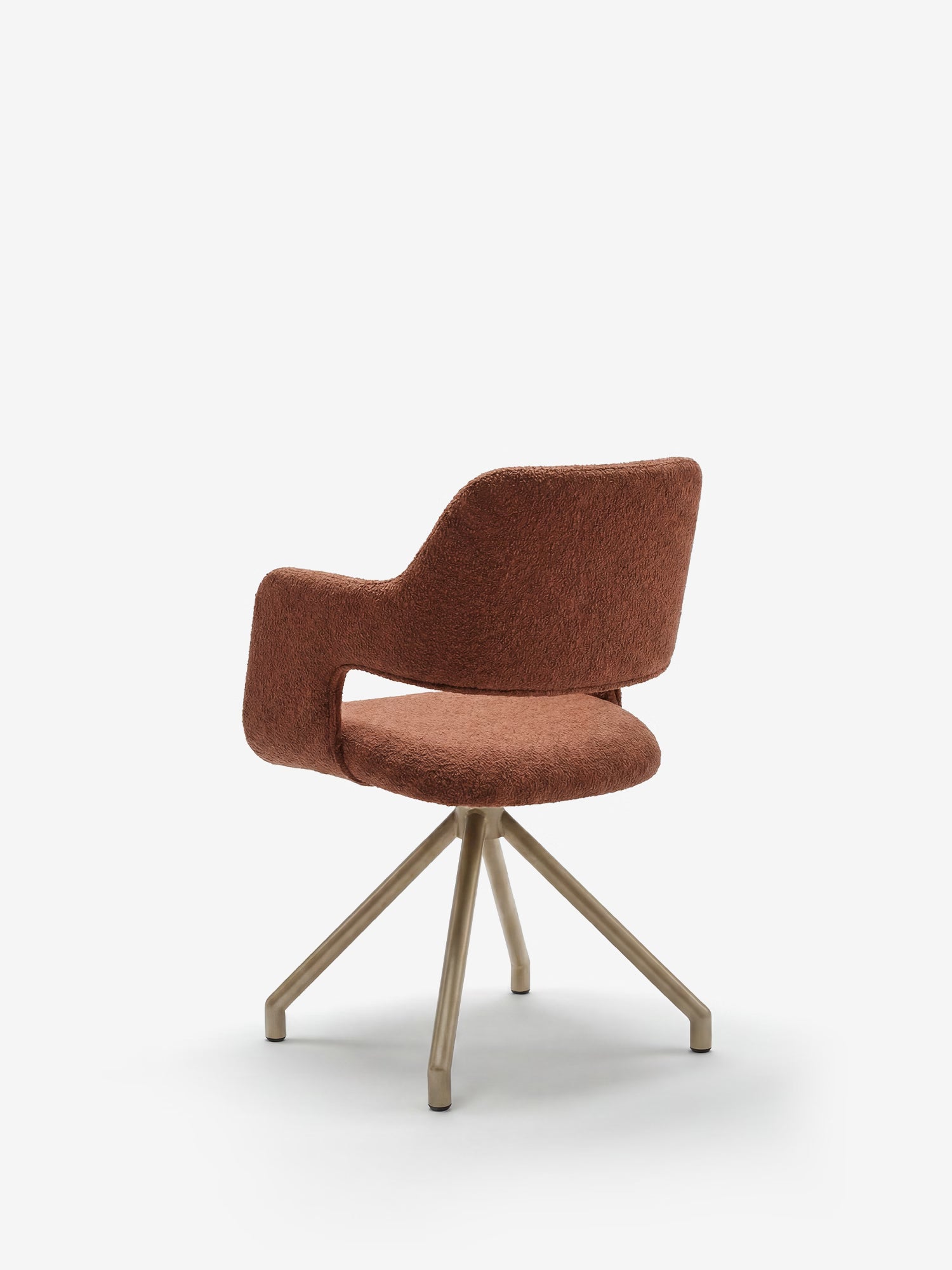 La Zefira di Divani.Store è una poltrona di design imbottita con braccioli, rivestita in tessuto effetto cotone color ruggine, con schienale traforato e base in metallo color champagne a quattro gambe inclinate. Sfondo bianco semplice.