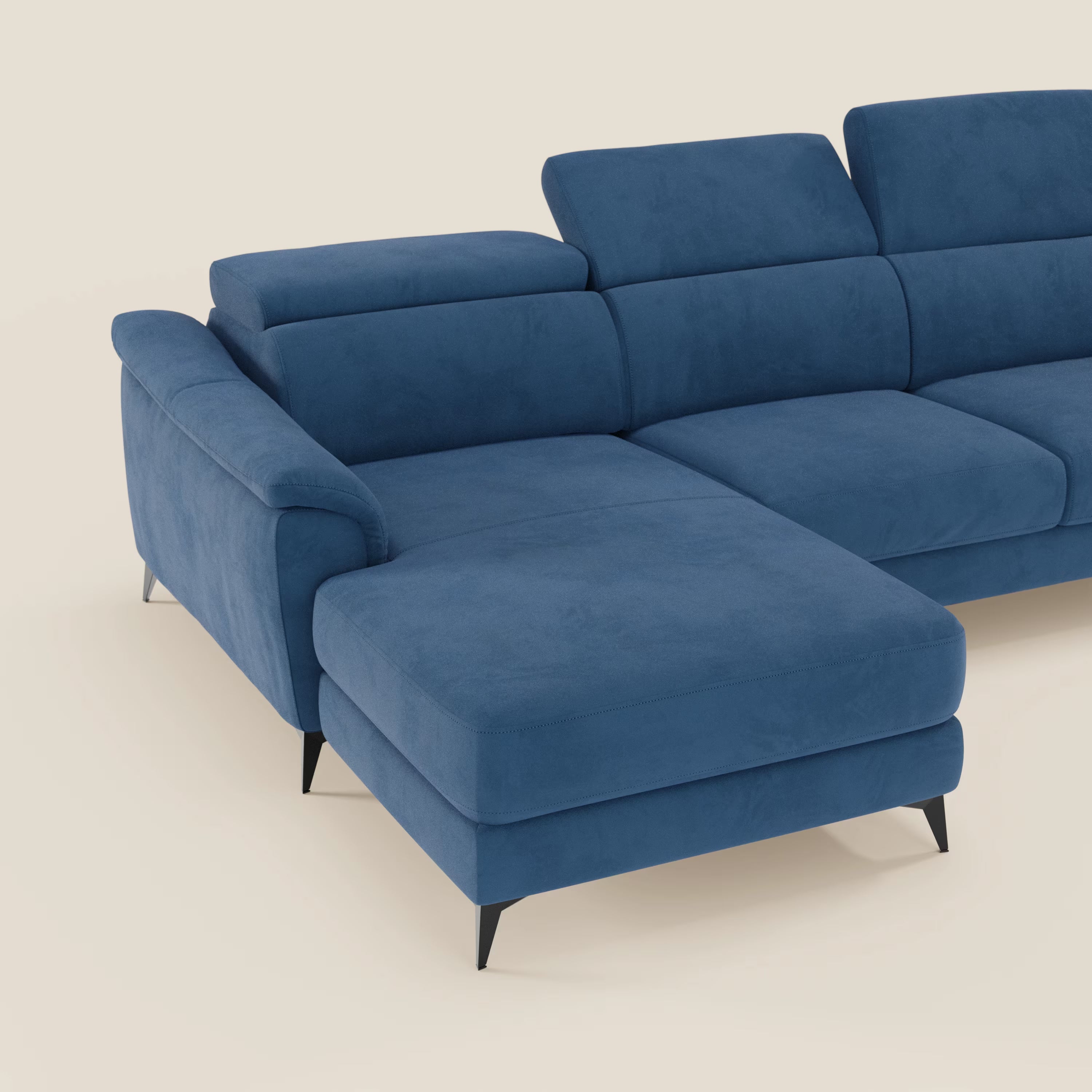 Il divano Arcos con penisola di Divani.Store è caratterizzato da gambe alte, poggiatesta regolabili e rivestimento in microfibra impermeabile T11 blu dal comfort soffice, raffigurato con la chaise longue a sinistra su uno sfondo beige chiaro.