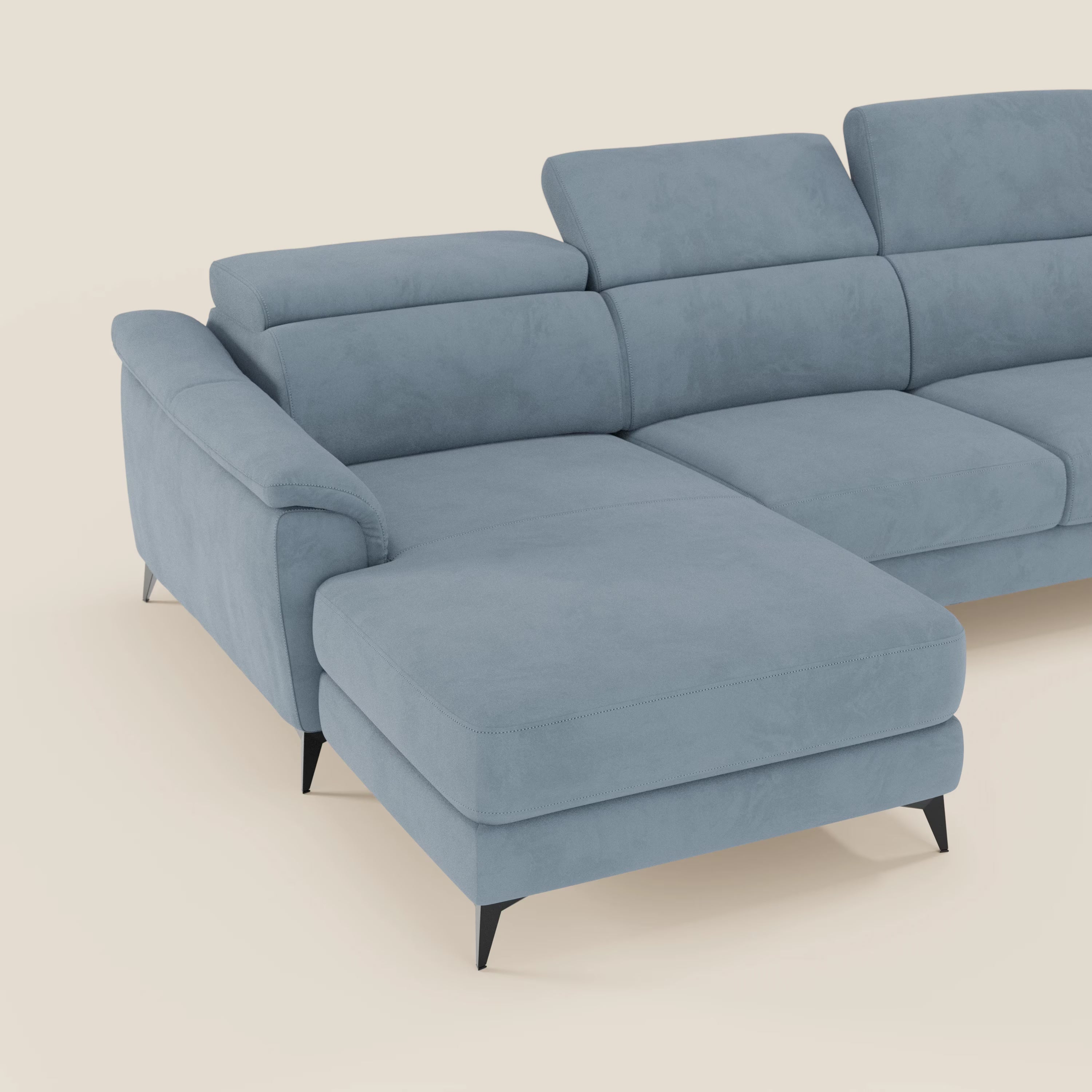 L'Arcos Divano con penisola di Divani.Store è dotato di microfibra impermeabile T11 carta da zucchero, poggiatesta regolabili, gambe alte in metallo nero e chaise longue, qui su un semplice sfondo beige.