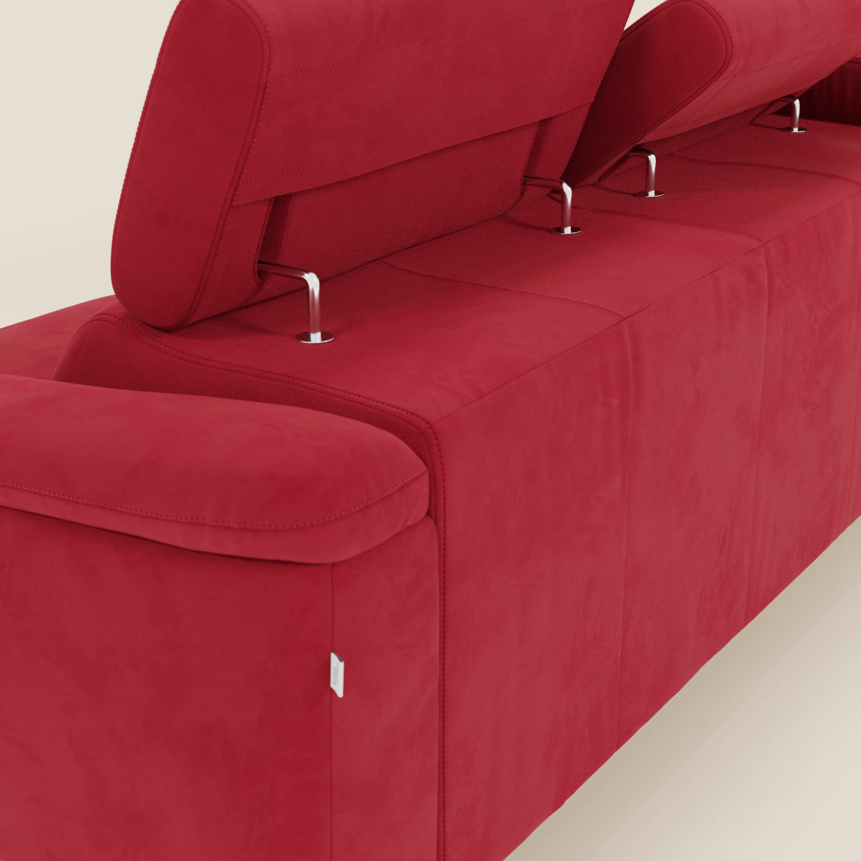 Un primo piano di Arcos Divano con penisola di Divani.Store mostra la microfibra impermeabile rossa, le gambe alte, i poggiatesta reclinabili, i braccioli morbidi e una piccola etichetta bianca, il tutto su uno sfondo chiaro.