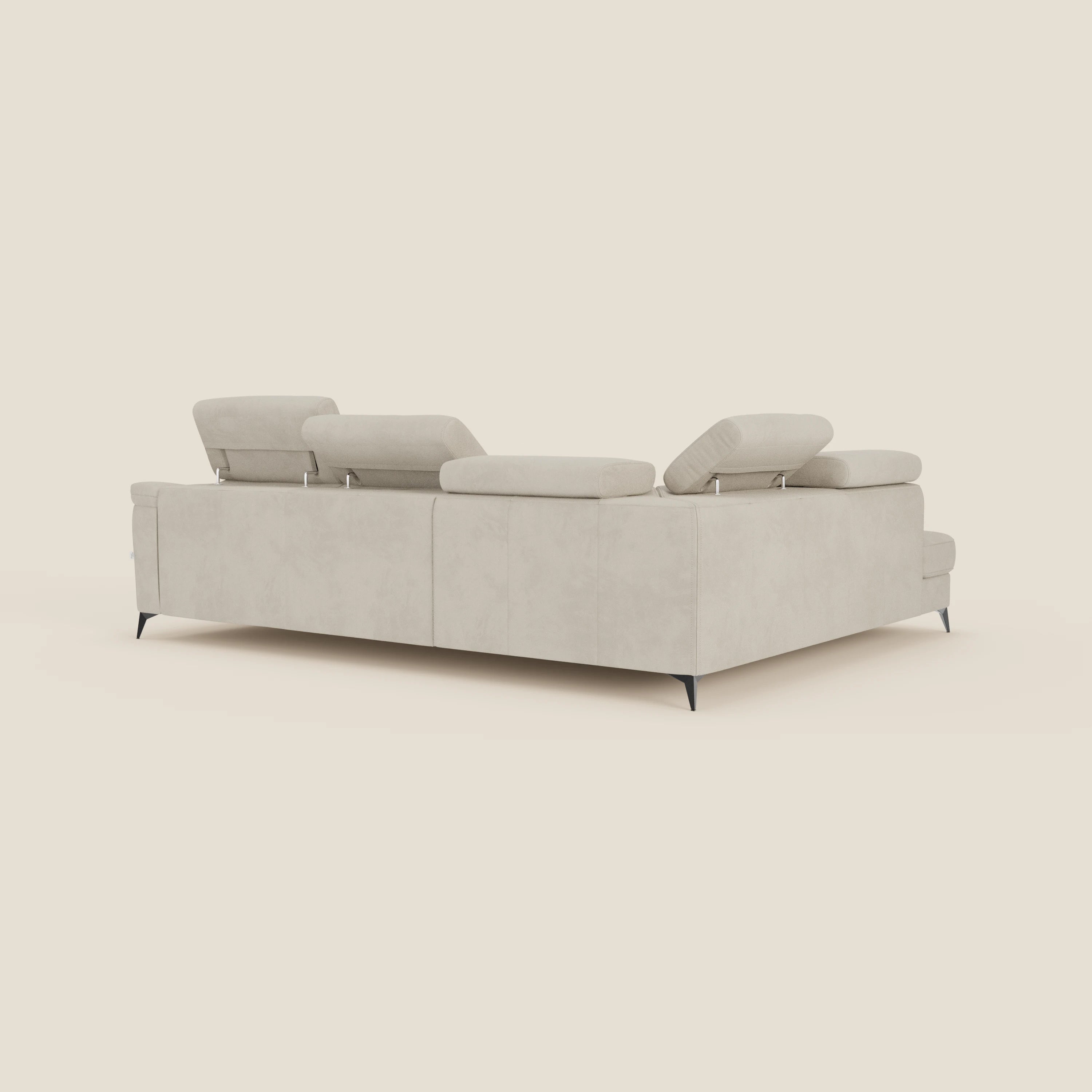 Il divano angolare Arcos di Divani.Store, presentato nella versione posteriore e laterale in microfibra impermeabile T11 panna, è caratterizzato da alte gambe nere, poggiatesta regolabili e linee pulite: il suo look minimalista spicca su un solido sfondo bianco sporco.