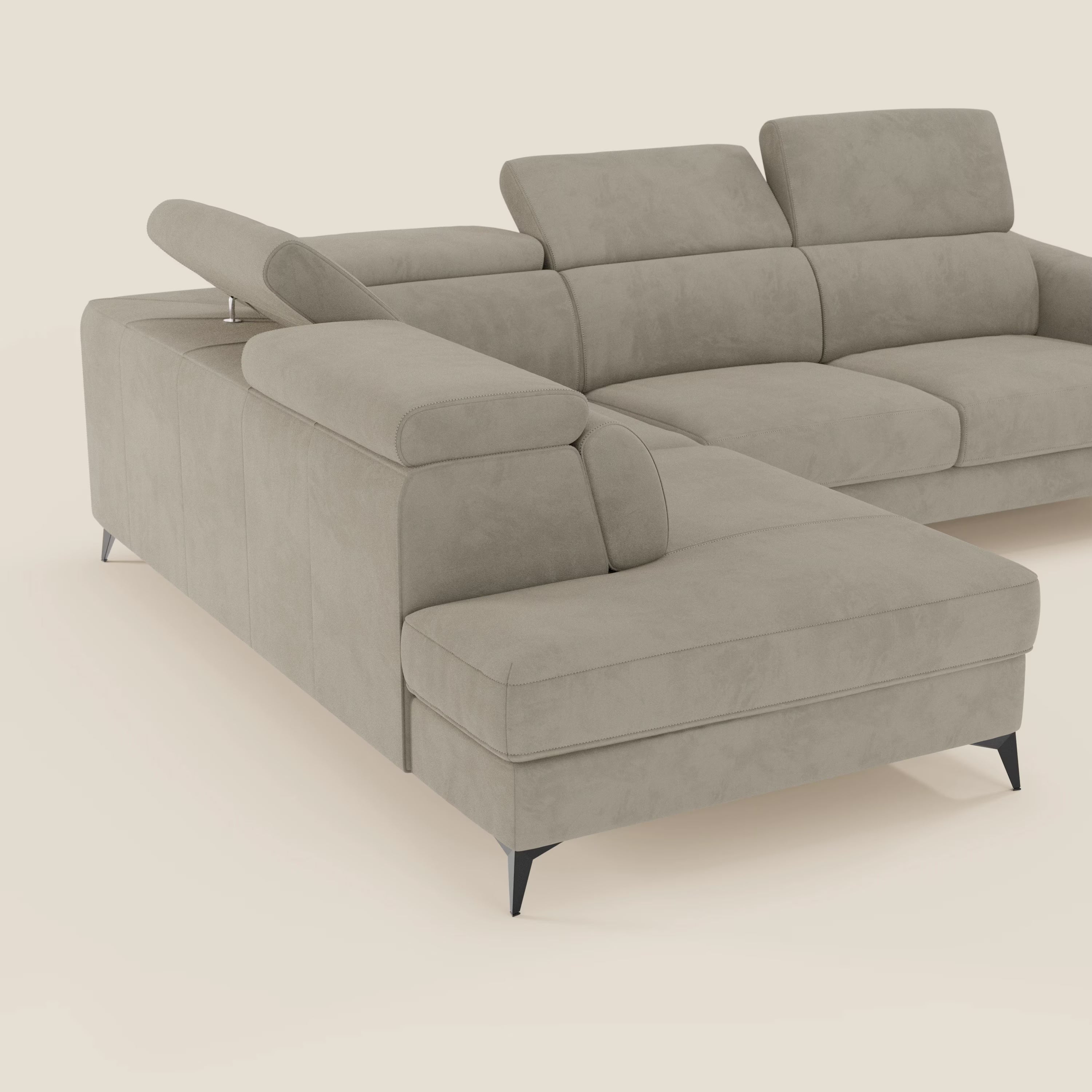 Arcos Divano angolare di Divani.Store è caratterizzato da gambe alte, poggiatesta regolabili e microfibra impermeabile T11 taupe. Il suo design moderno a forma di L, con cuscini in tessuto, spicca su un semplice sfondo bianco sporco.