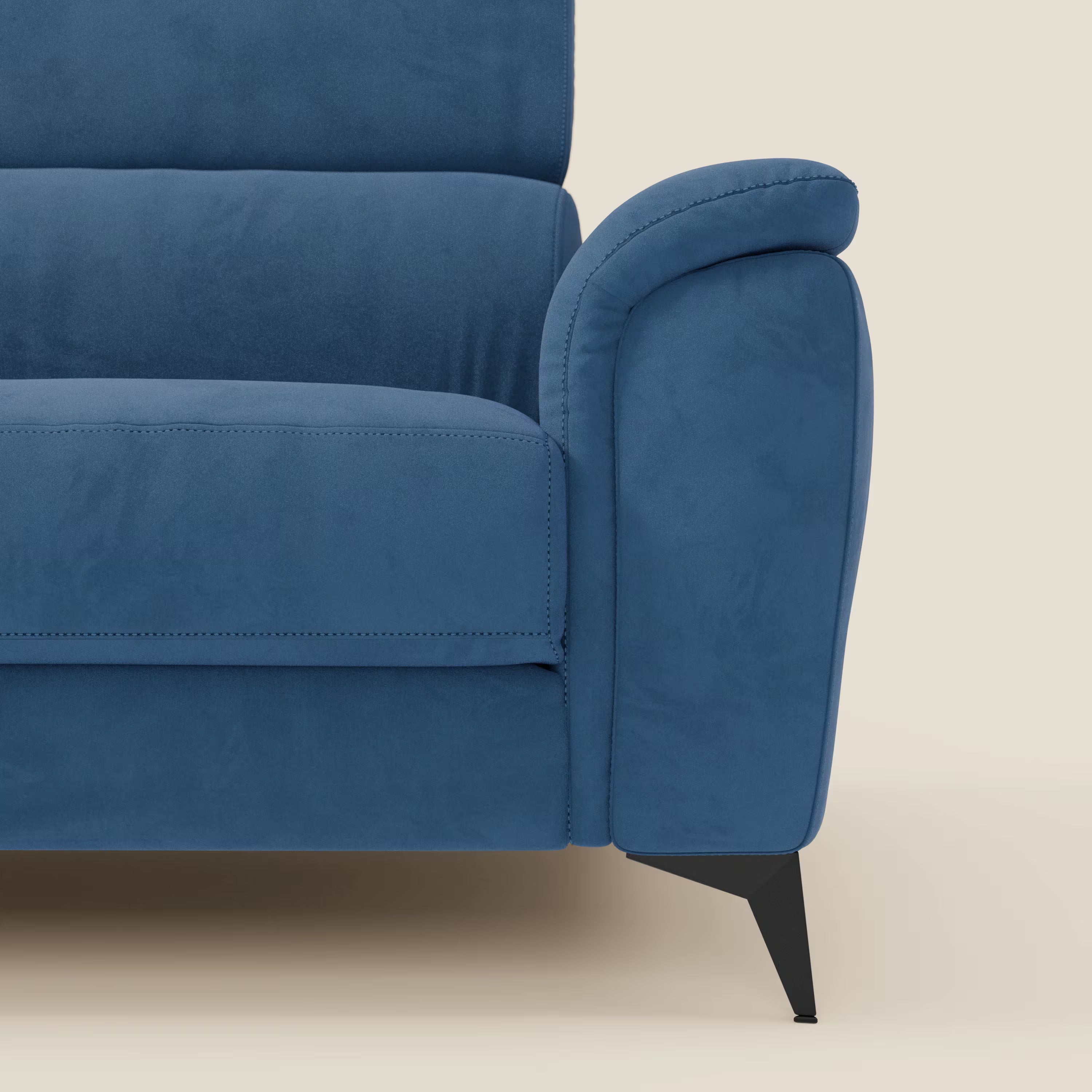 Primo piano del lato destro di Arcos Divano 3 posti di Divani.Store in microfibra impermeabile T11 blu, con cuscini in feltro, gamba angolata in metallo nero, poggiatesta reclinabile e cuciture in evidenza su sfondo beige.