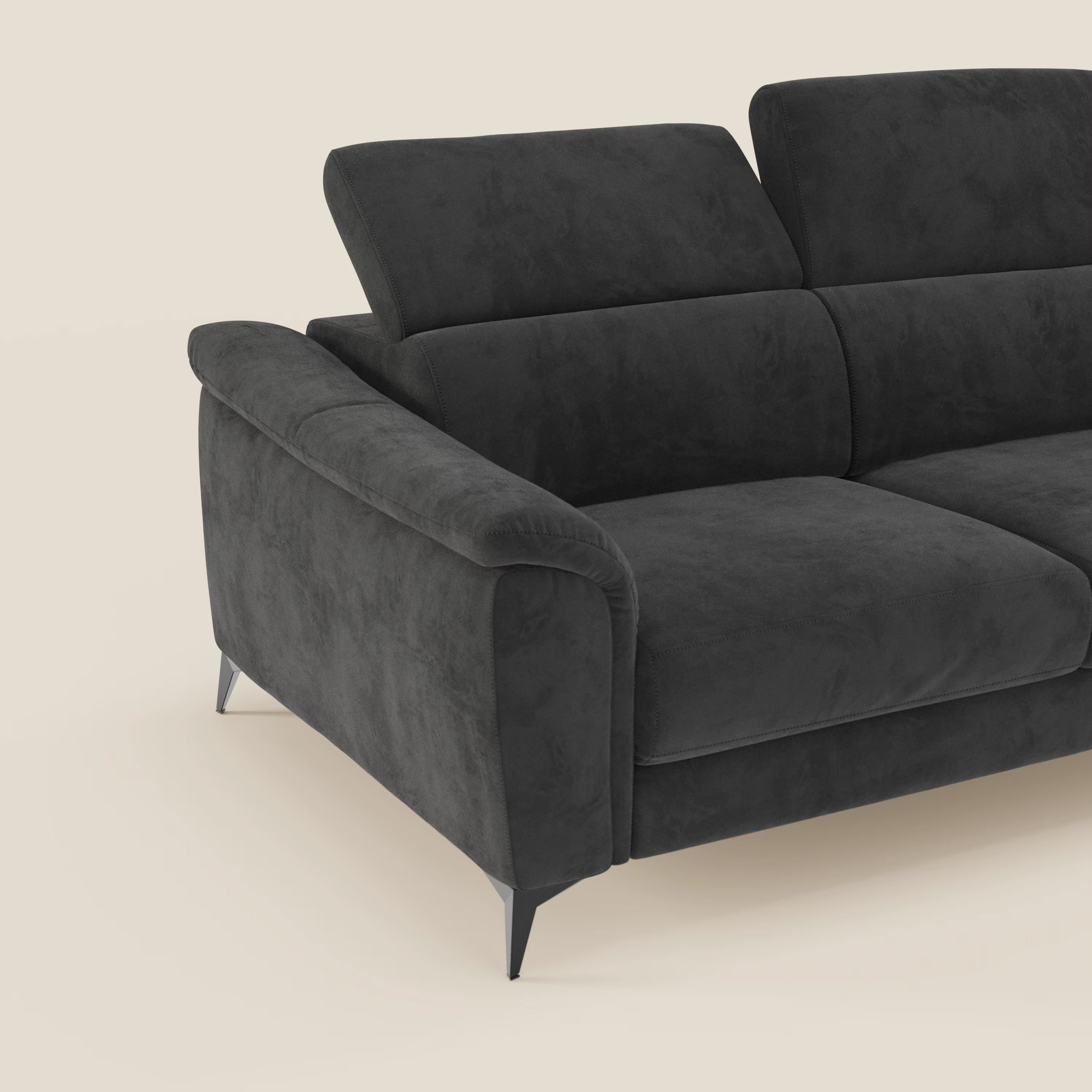 Un elegante Arcos Divano 3 posti di Divani.Store in microfibra impermeabile nera T11, con gambe alte e poggiatesta regolabili, è mostrato parzialmente con il bracciolo sinistro e due cuscini di seduta su uno sfondo beige semplice.