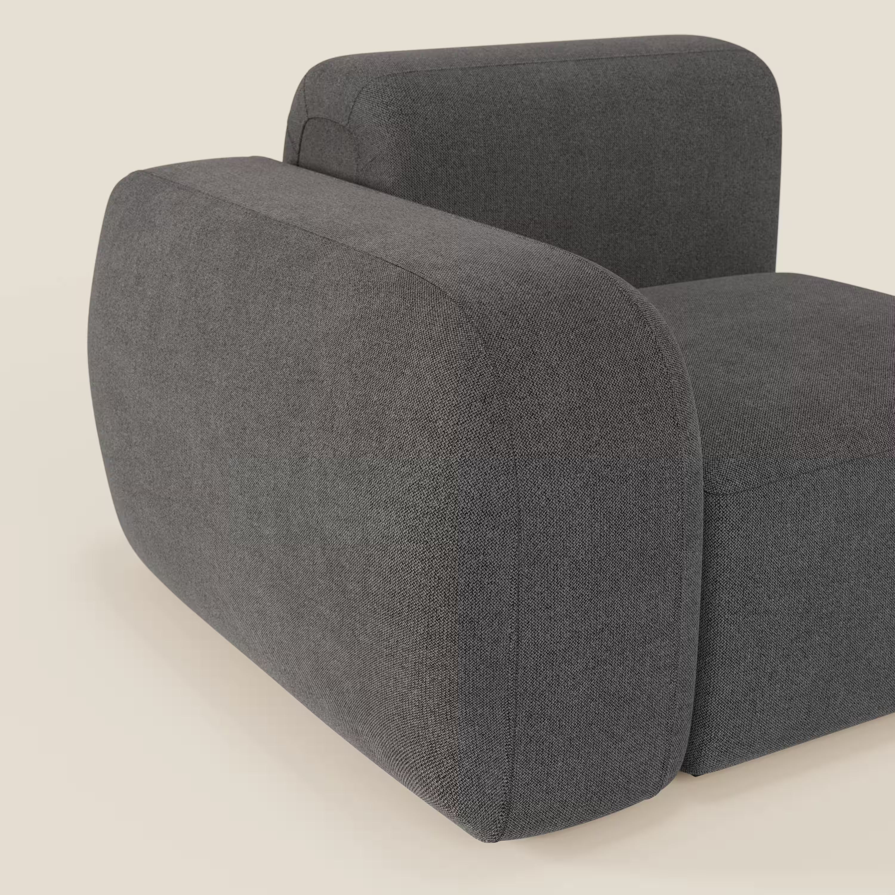 Il BonBon modulo terminale 105 cm di Divani.Store è caratterizzato da braccioli e schienale spessi e arrotondati rivestiti in tessuto smacchiabile T23 antracite, che offre una sensazione di morbidezza e texture e un look minimalista su uno sfondo crema chiaro.