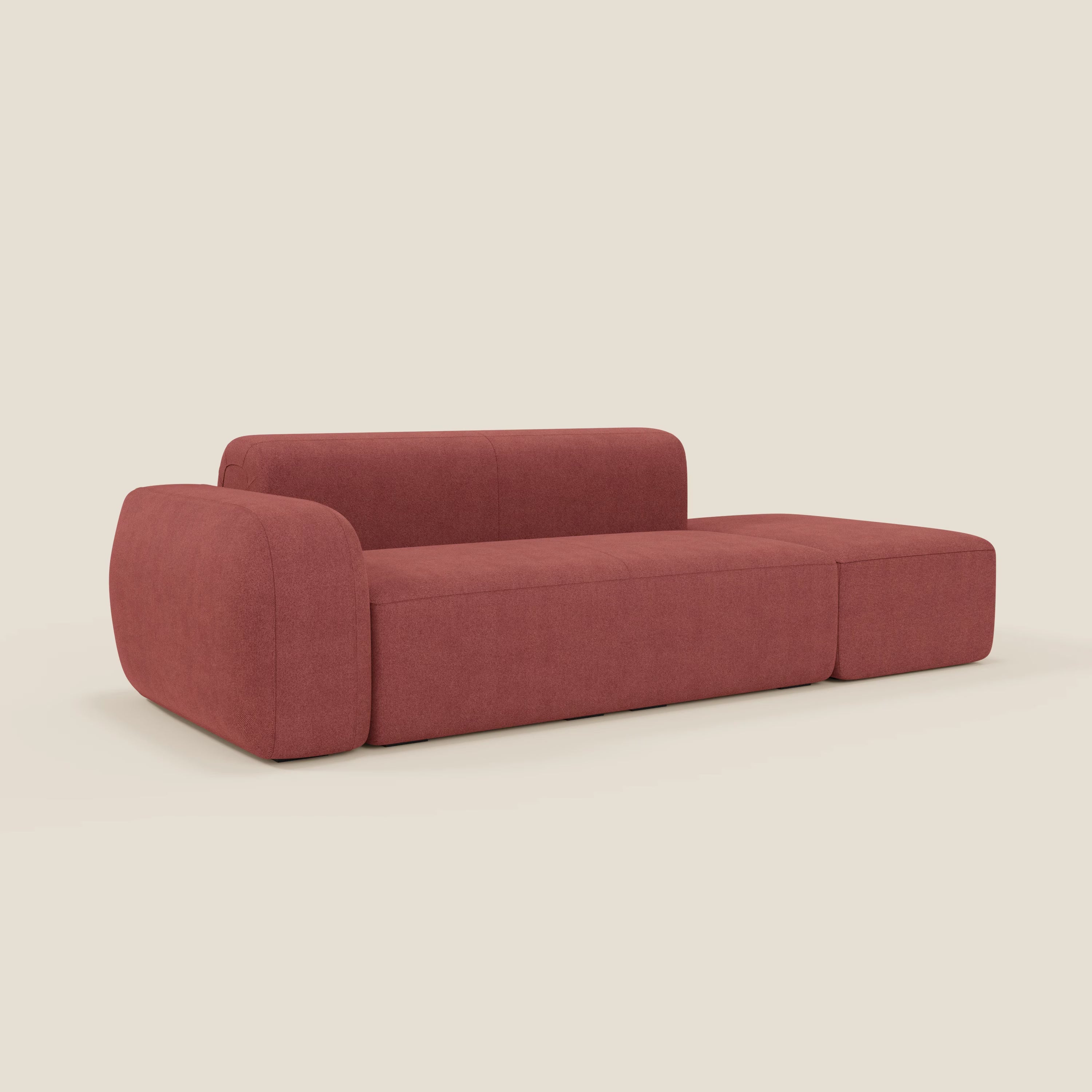 Il divano componibile BonBon Divani.Store in tessuto smacchiabile T23 rosso ciliegia è caratterizzato da ampi braccioli a sinistra, uno schienale basso e una spaziosa seduta senza gambe dalle linee minimaliste, su uno sfondo beige chiaro.