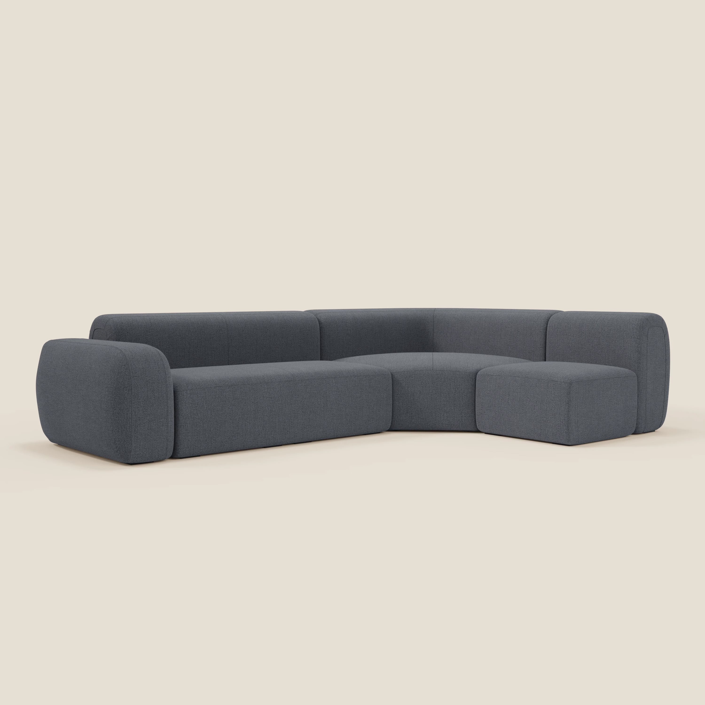Il divano angolare componibile e modulare BonBon di Divani.Store, in tessuto smacchiabile T23 blu grafite, presenta una moderna forma a L, bordi arrotondati, schienali bassi, cuscini spessi e un design minimalista senza gambe a vista.