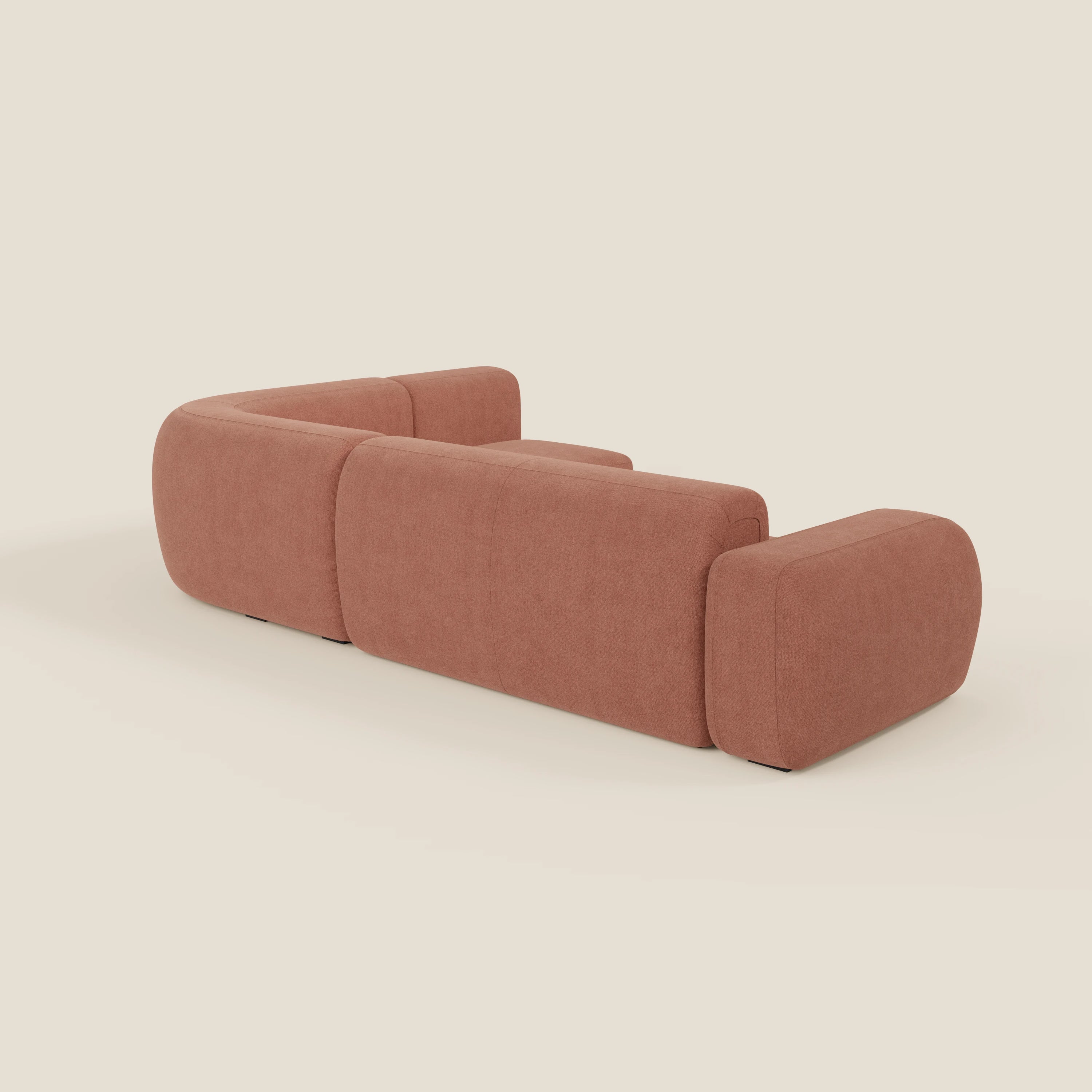 Il divano angolare componibile e modulare BonBon di Divani.Store è caratterizzato da un design moderno e minimalista con bordi arrotondati e linee squadrate, rivestito in tessuto smacchiabile T23 pesca. Mostrato di schiena e di lato su uno sfondo bianco sporco.