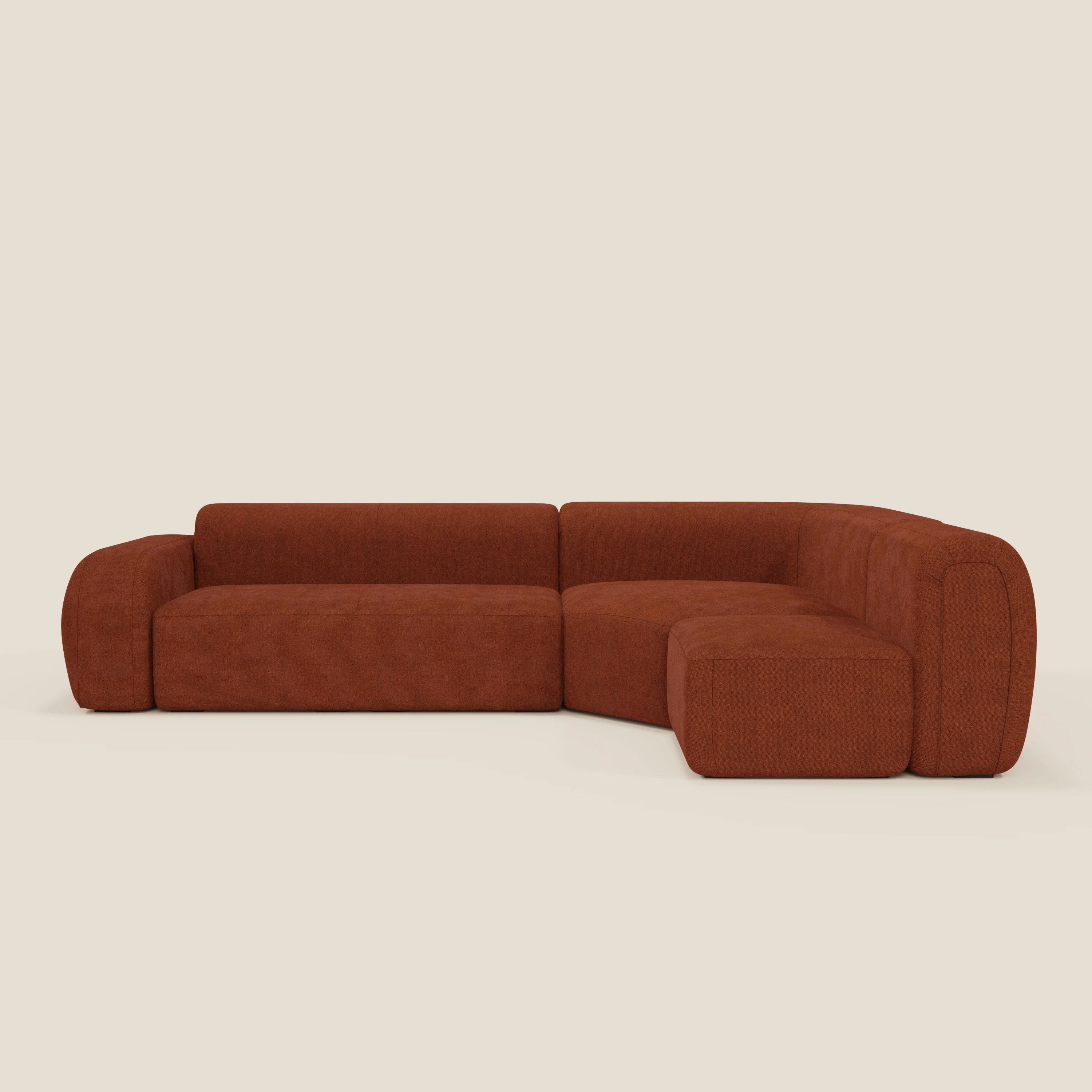 Il divano angolare componibile e modulare BonBon di Divani.Store è caratterizzato da bordi arrotondati, schienali bassi e tessuto smacchiabile T23 color ruggine. Le sue linee pulite e il design minimalista contemporaneo spiccano su uno sfondo neutro.