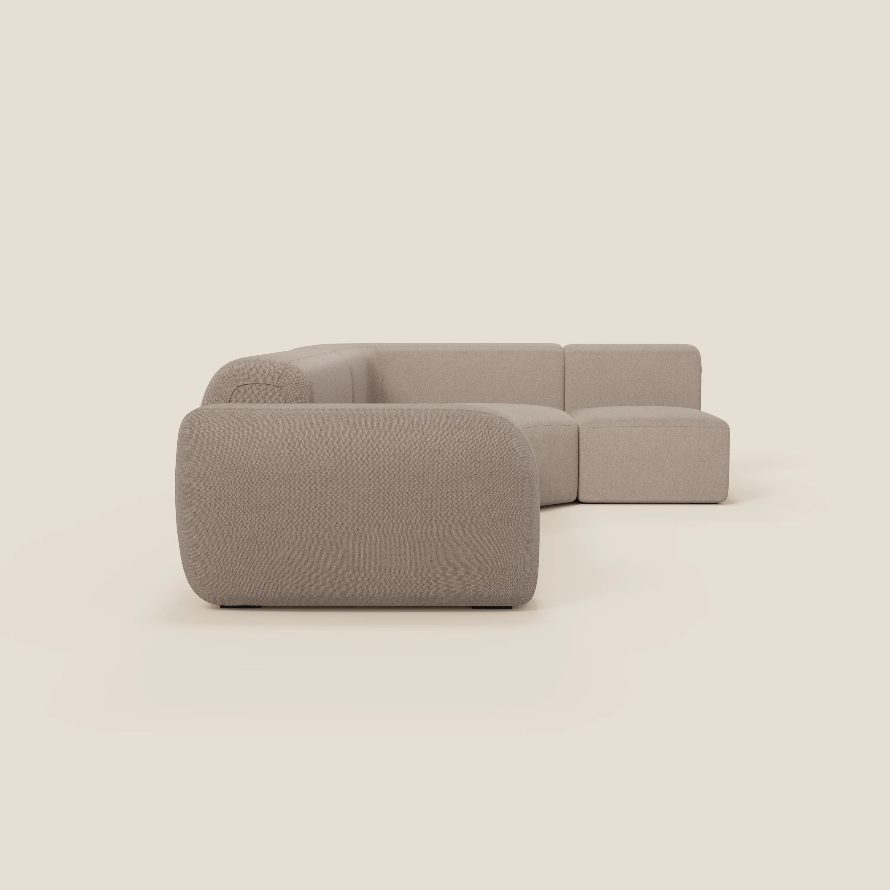 Il divano angolare componibile e modulare BonBon di Divani.Store, in tessuto smacchiabile T23 tortora, è caratterizzato da bordi lisci e arrotondati, cuscini a basso profilo e un design minimalista senza gambe, su uno sfondo color crema chiaro.
