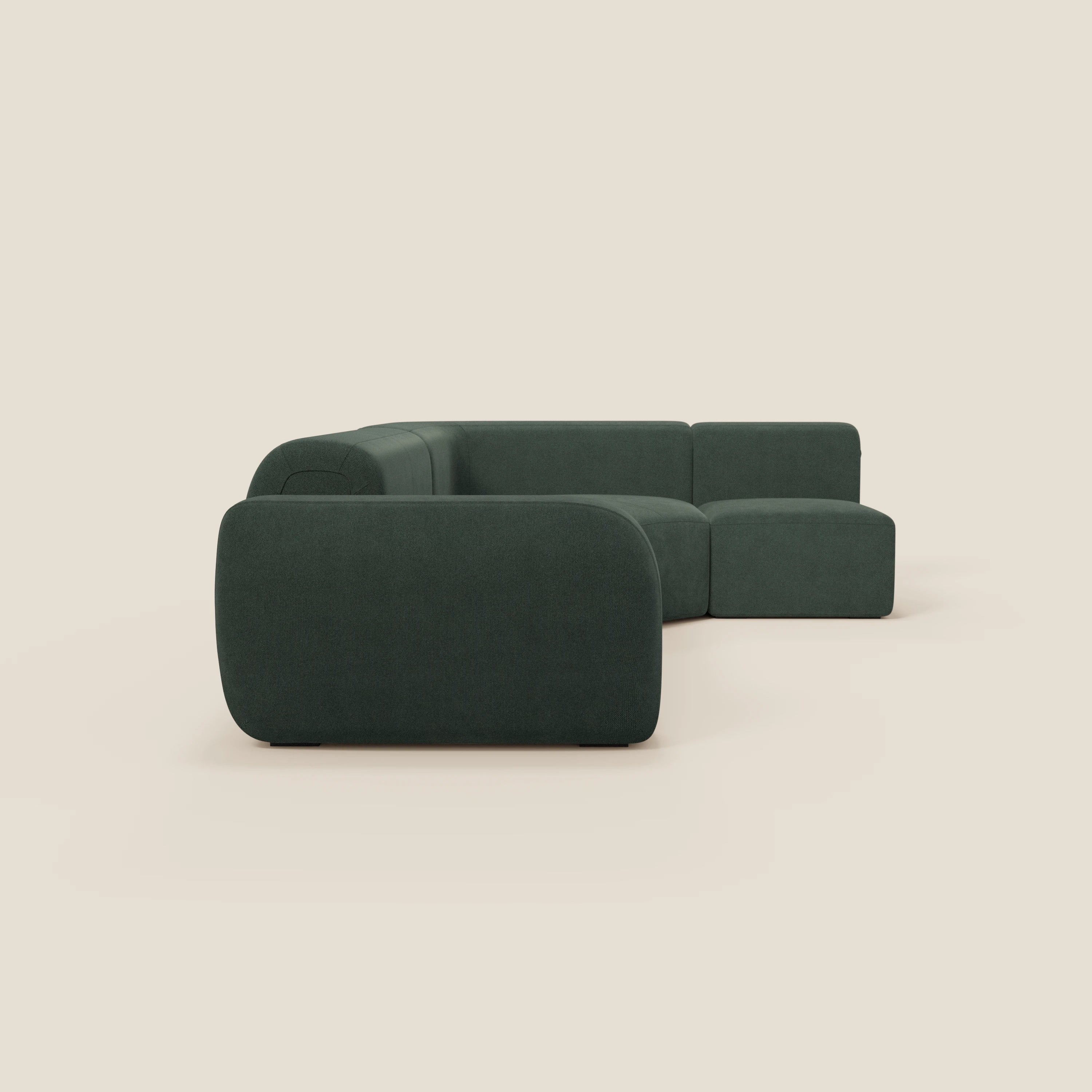 Il divano angolare componibile e modulare BonBon di Divani.Store, in tessuto antimacchia T23 verde, è caratterizzato da uno schienale basso, bordi arrotondati e cuscini morbidi per un design minimalista a forma di L su uno sfondo beige senza cuciture. Prodotto in Italia.