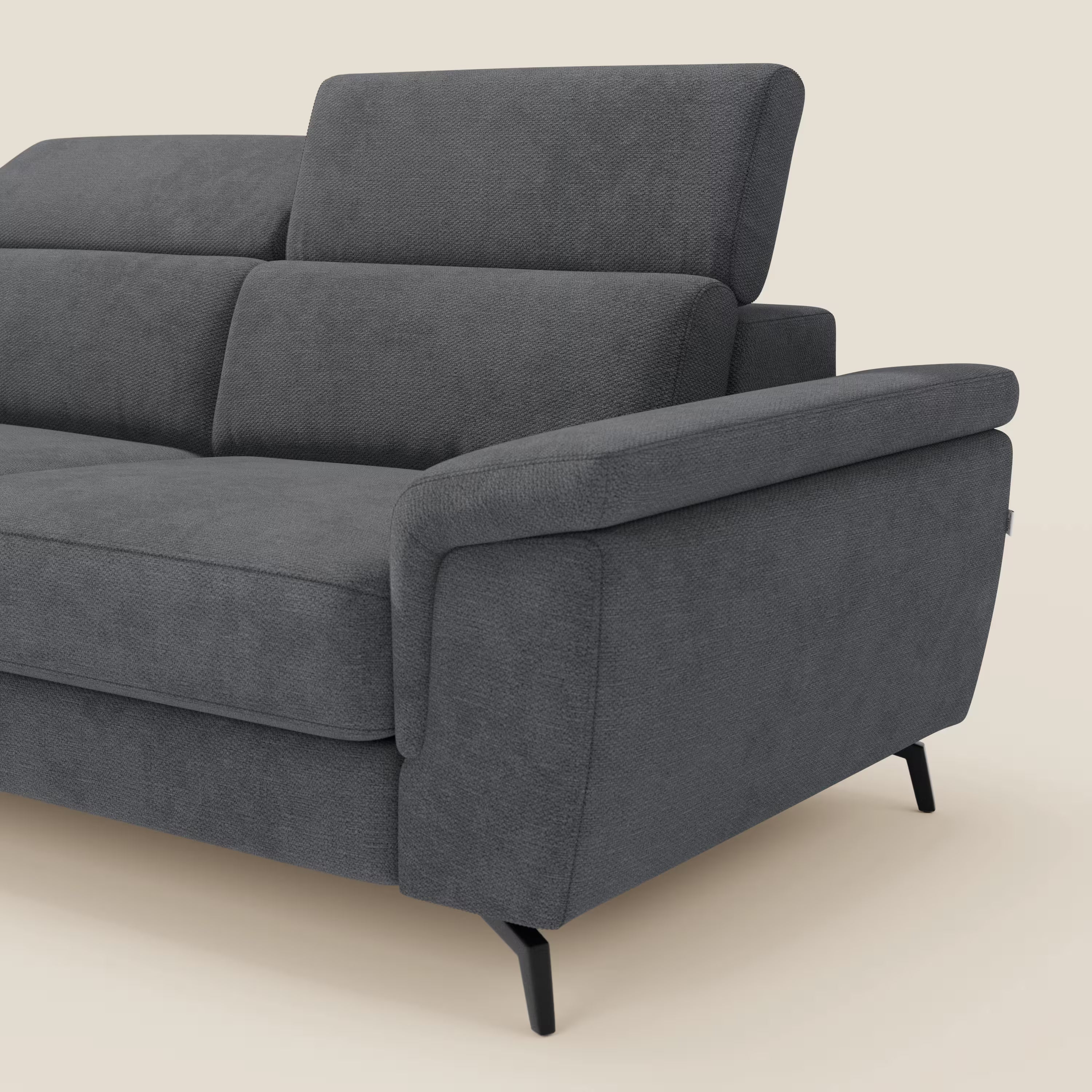 Estro Divano 3 posti con pouf estraibile di Divani.Store è caratterizzato da poggiatesta reclinabili e tessuto impermeabile T14 antracite. Su uno sfondo beige, solo in parte visibile, presenta ampi braccioli ed eleganti gambe in metallo nero per un look moderno.