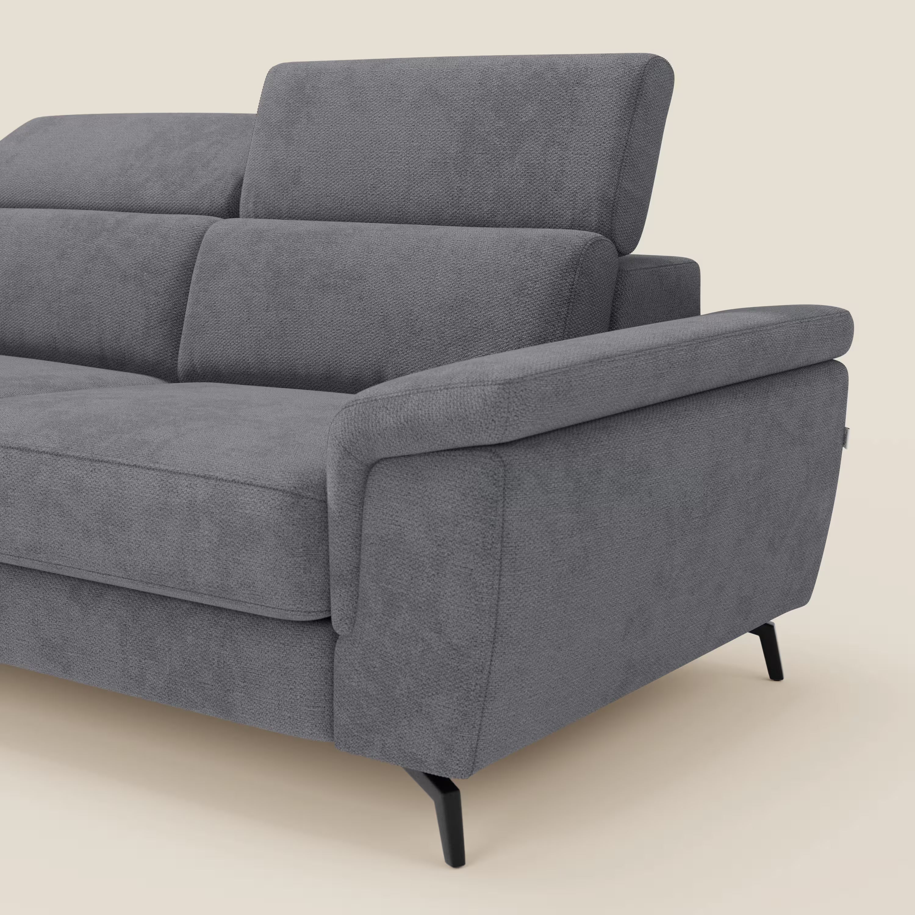 Estro Divano 3 posti con pouf estraibile di Divani.Store è caratterizzato da poggiatesta reclinabili, ampi braccioli imbottiti, tessuto impermeabile T14 grigio ed eleganti gambe angolate in metallo nero. In parte su uno sfondo beige chiaro.