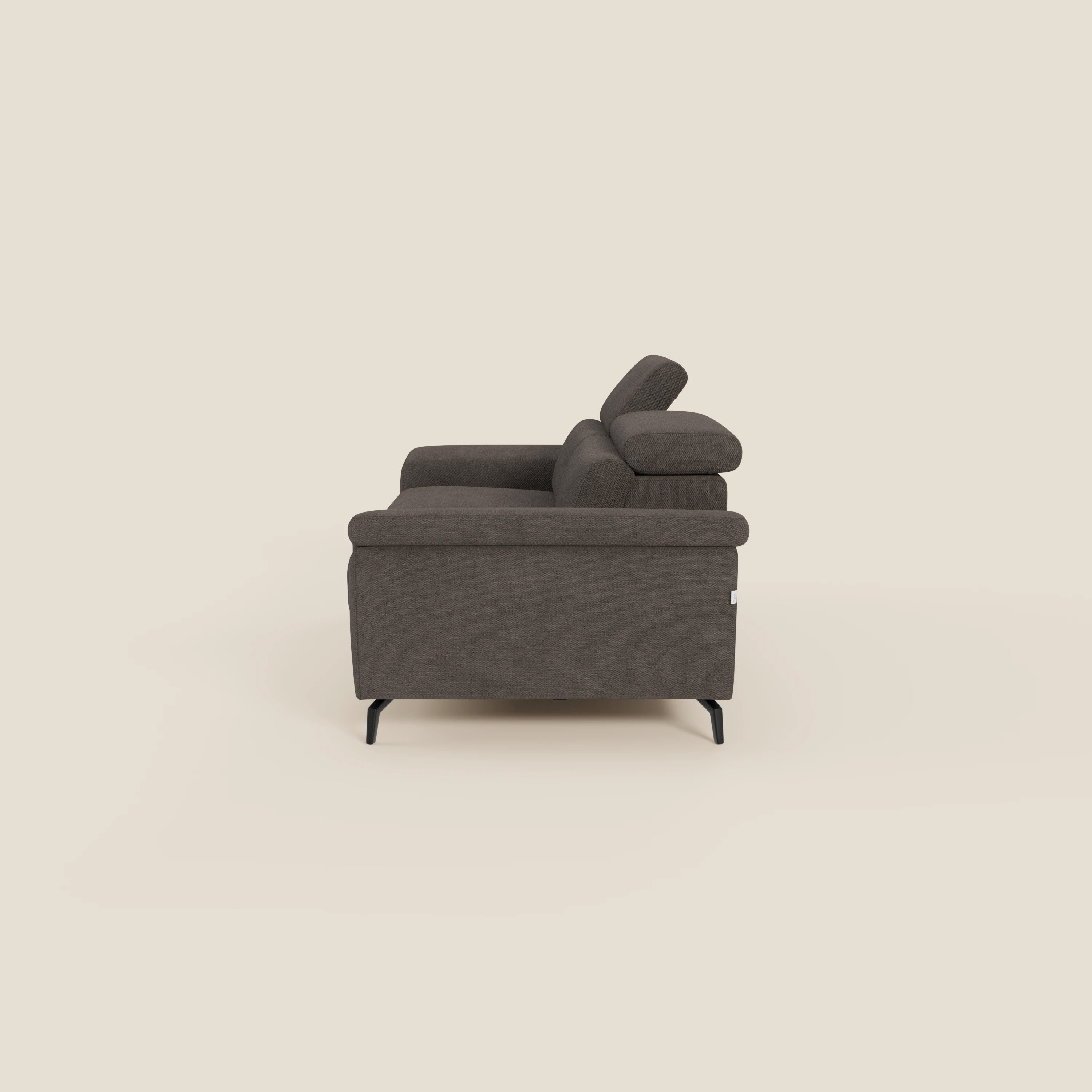 L'Estro Divano 3 posti con pouf estraibile di Divani.Store, in tessuto impermeabile T14 marrone, è caratterizzato da poggiatesta reclinabili e sottili gambe in metallo nero. La sua silhouette squadrata spicca su uno sfondo bianco sporco.