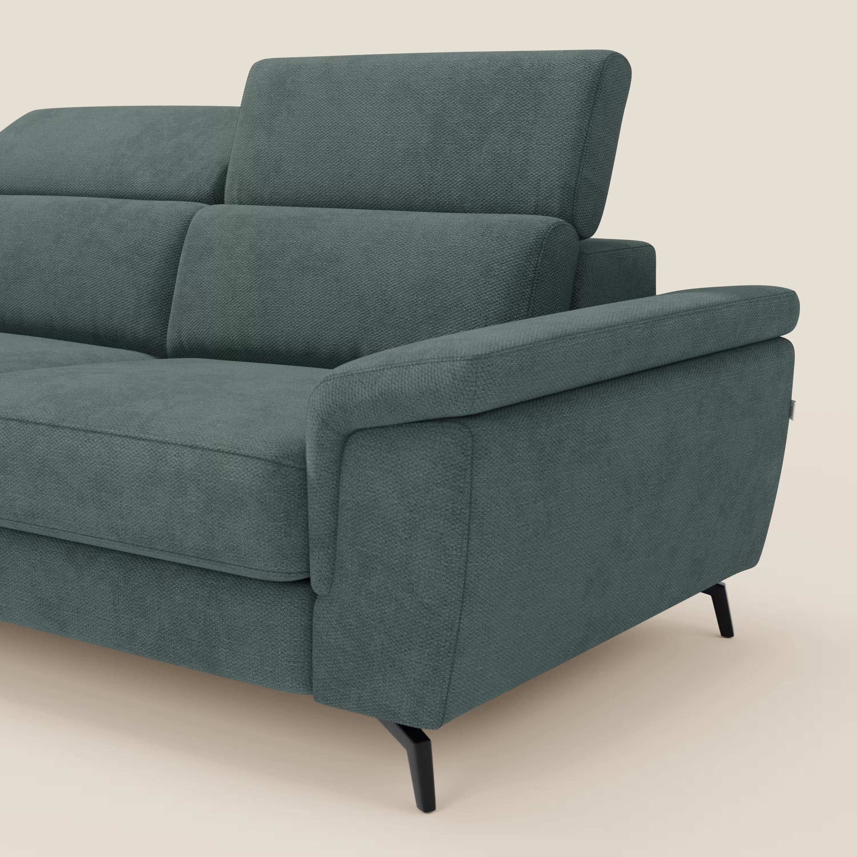 Estro Divano 3 posti di Divani.Store è caratterizzato da poggiatesta reclinabili, ampi braccioli imbottiti e gambe in metallo nero con tessuto impermeabile verde T14. In figura, su sfondo beige, un primo piano di un braccio e della seduta.