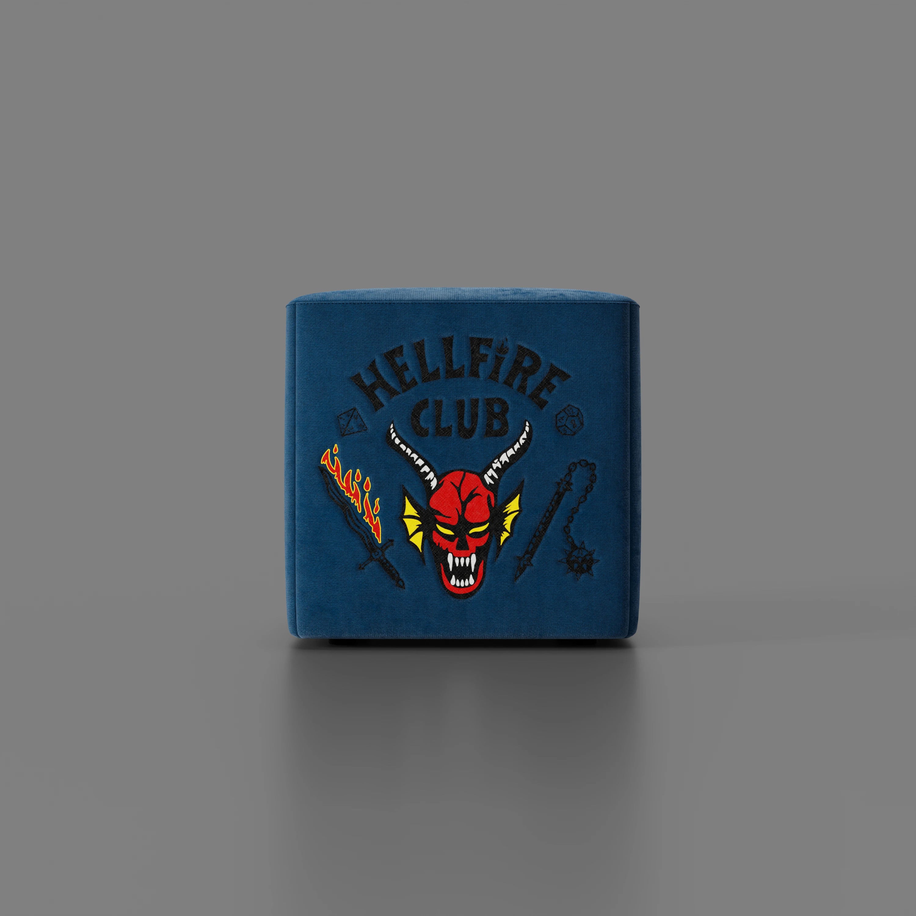 Il pouf Cube Hellfire club Stranger Things Edition di Divani.Store, in blu, presenta l'iconico design dell'"Hellfire Club" - demone rosso, spada infuocata, mazza e frusta a catena - e si distingue come pezzo in edizione limitata.
