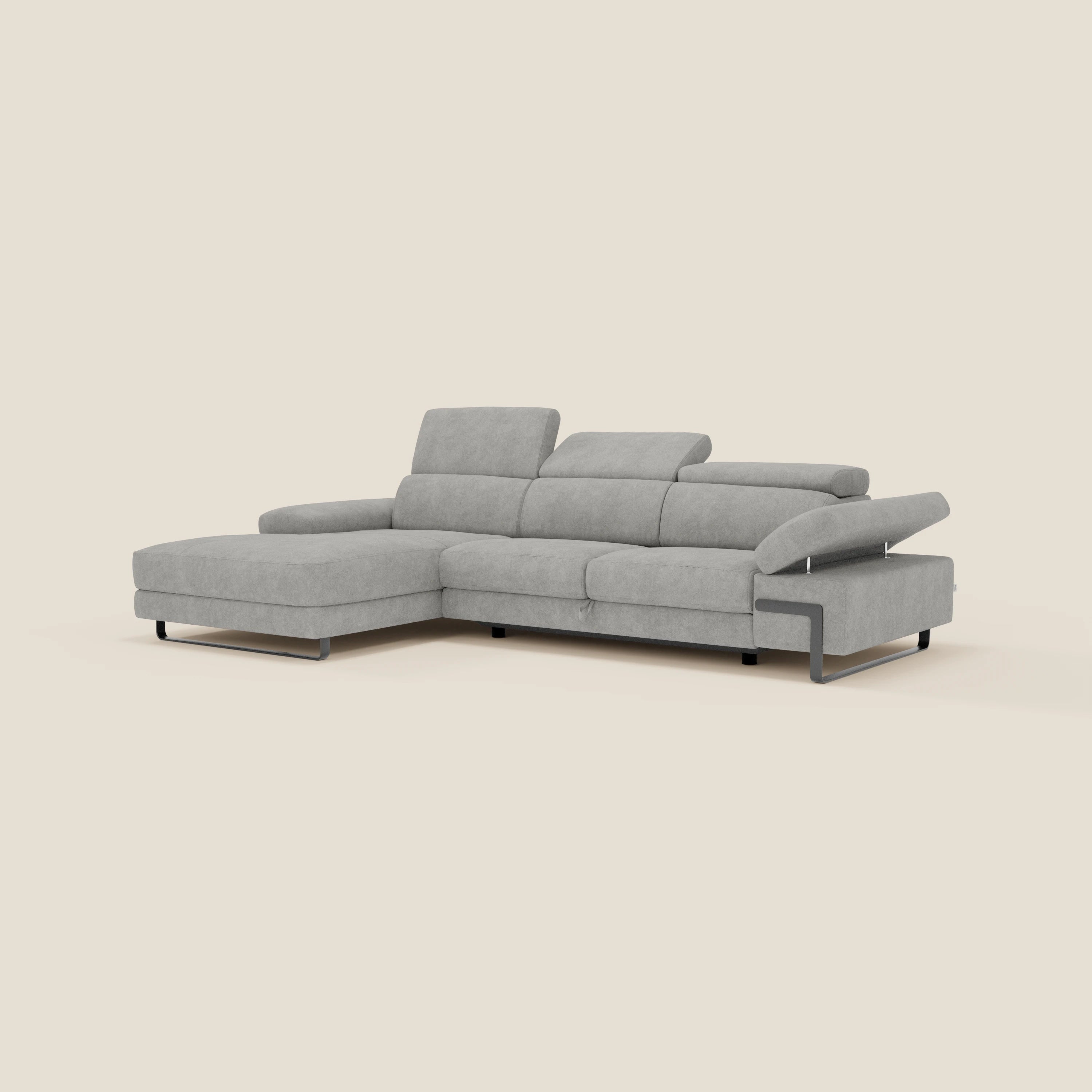 Il divano angolare estraibile Zayana di Divani.Store in T02 grigio chiaro vanta braccioli e poggiatesta regolabili, tessuto idrorepellente e gambe corte in metallo nero per un look moderno e pratico su uno sfondo beige chiaro.