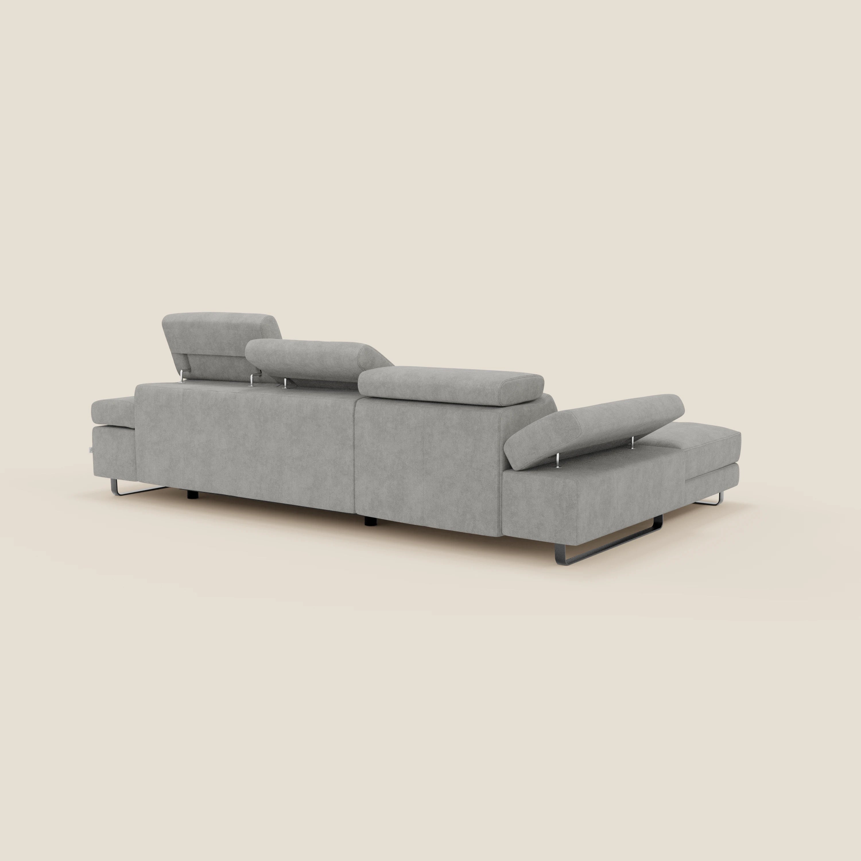 Il divano angolare estraibile Zayana di Divani.Store è caratterizzato da braccioli e poggiatesta reclinabili in tessuto impermeabile T02 grigio chiaro, linee moderne, gambe in metallo, ed è presentato dal retro su uno sfondo beige chiaro.