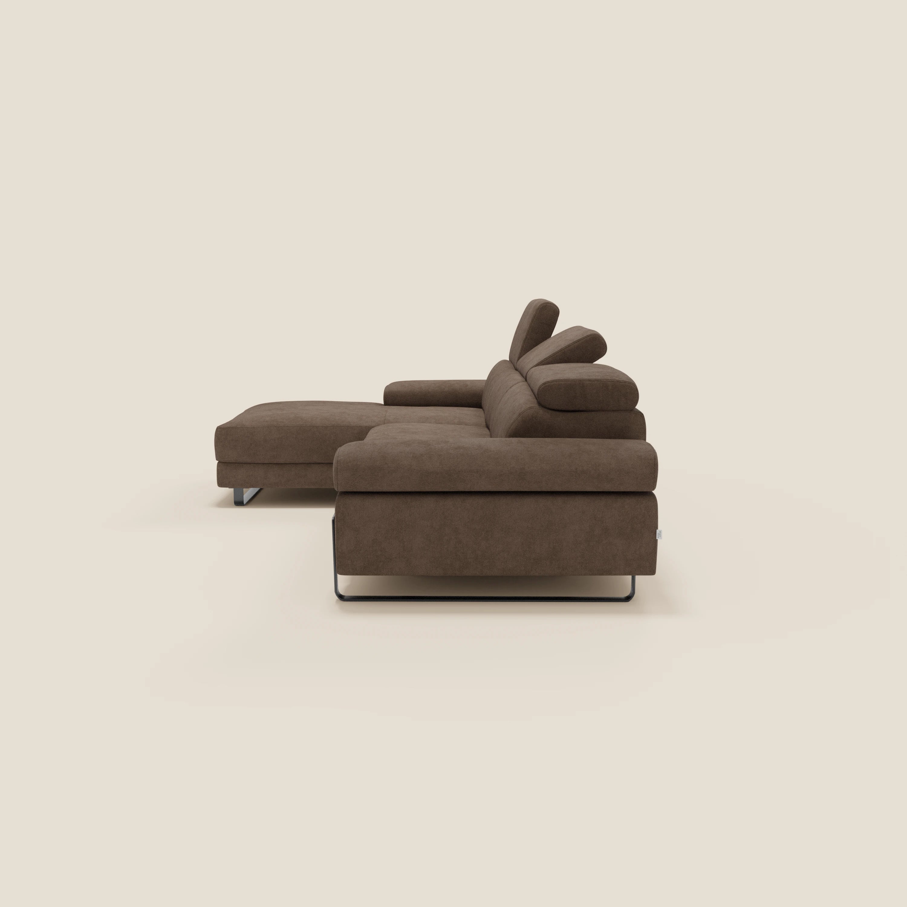 Il divano angolare estraibile Zayana di Divani.Store è caratterizzato da braccioli e poggiatesta reclinabili in tessuto impermeabile T02 marrone e sottili gambe in metallo nero, con chaise lounge a sinistra, su uno sfondo beige chiaro.
