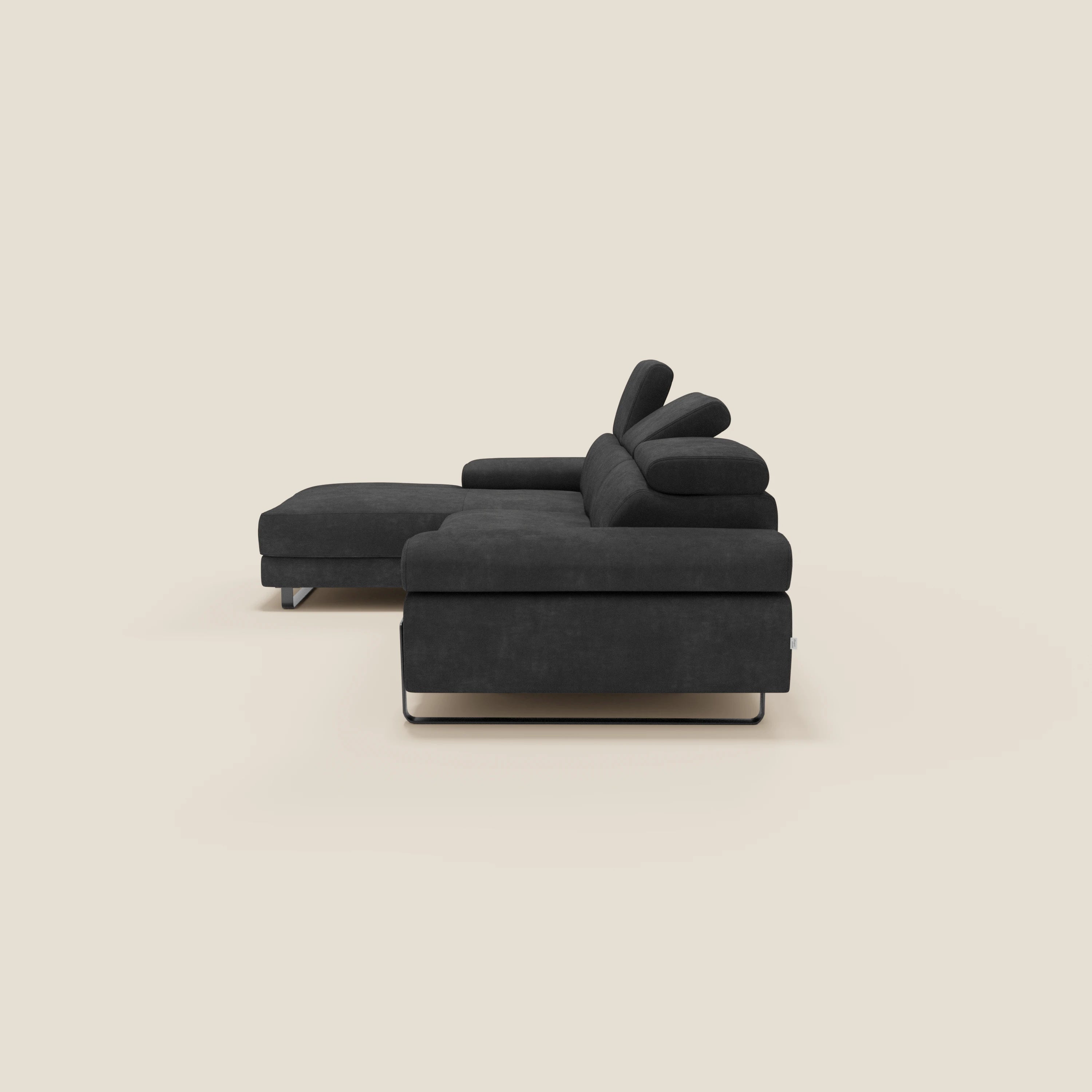 Il divano angolare estraibile Zayana di Divani.Store, in tessuto impermeabile nero T02, è caratterizzato da braccioli e poggiatesta reclinabili, eleganti gambe in metallo e una chaise lounge a sinistra, su uno sfondo beige chiaro.