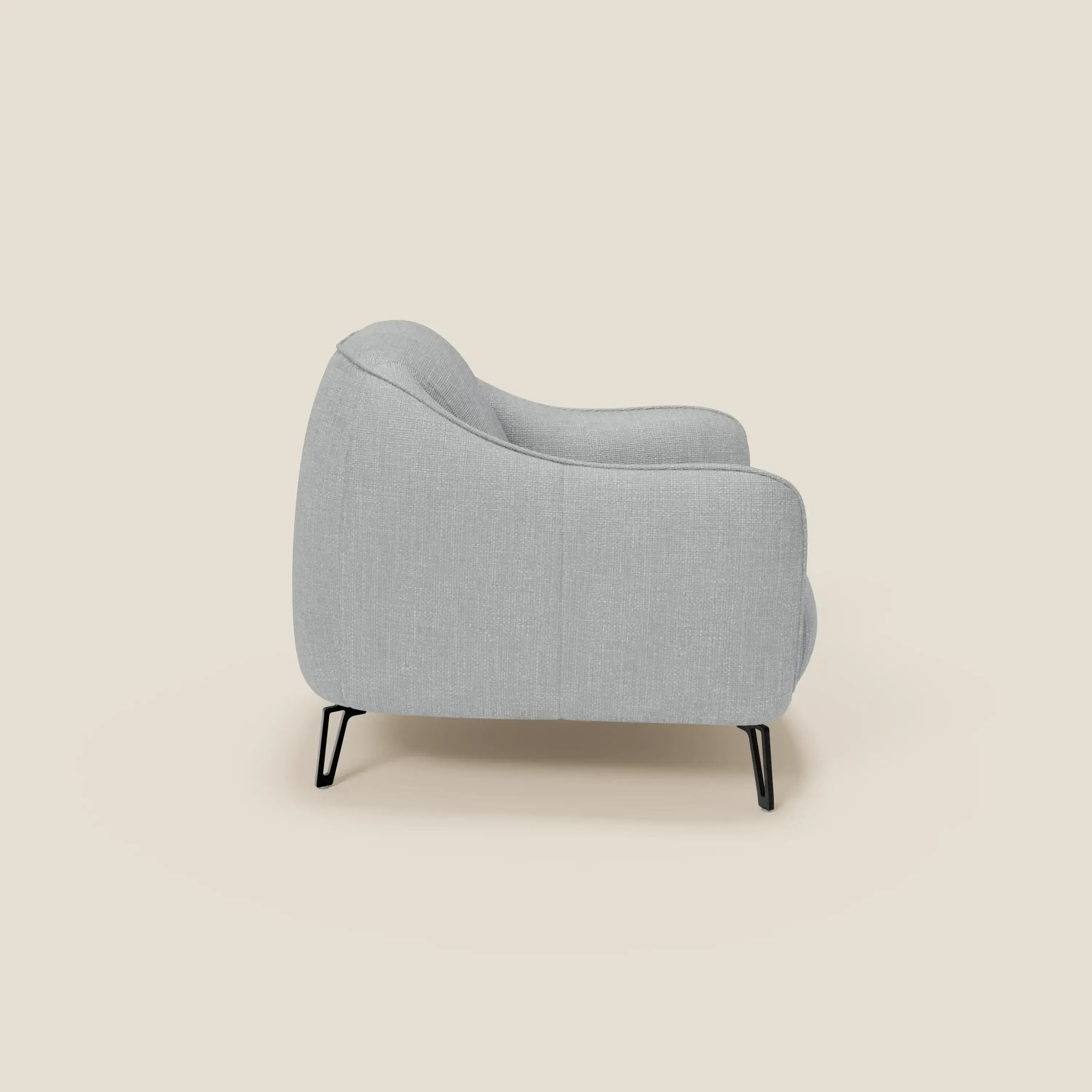 L'Avela Poltroncina di Divani.Store, in morbido tessuto T06 ghiaccio resistente all'acqua, si presenta con un profilo laterale dai bordi delicatamente arrotondati e gambe in metallo nero, con uno schienale alto per un comfort senza tempo e un look moderno.