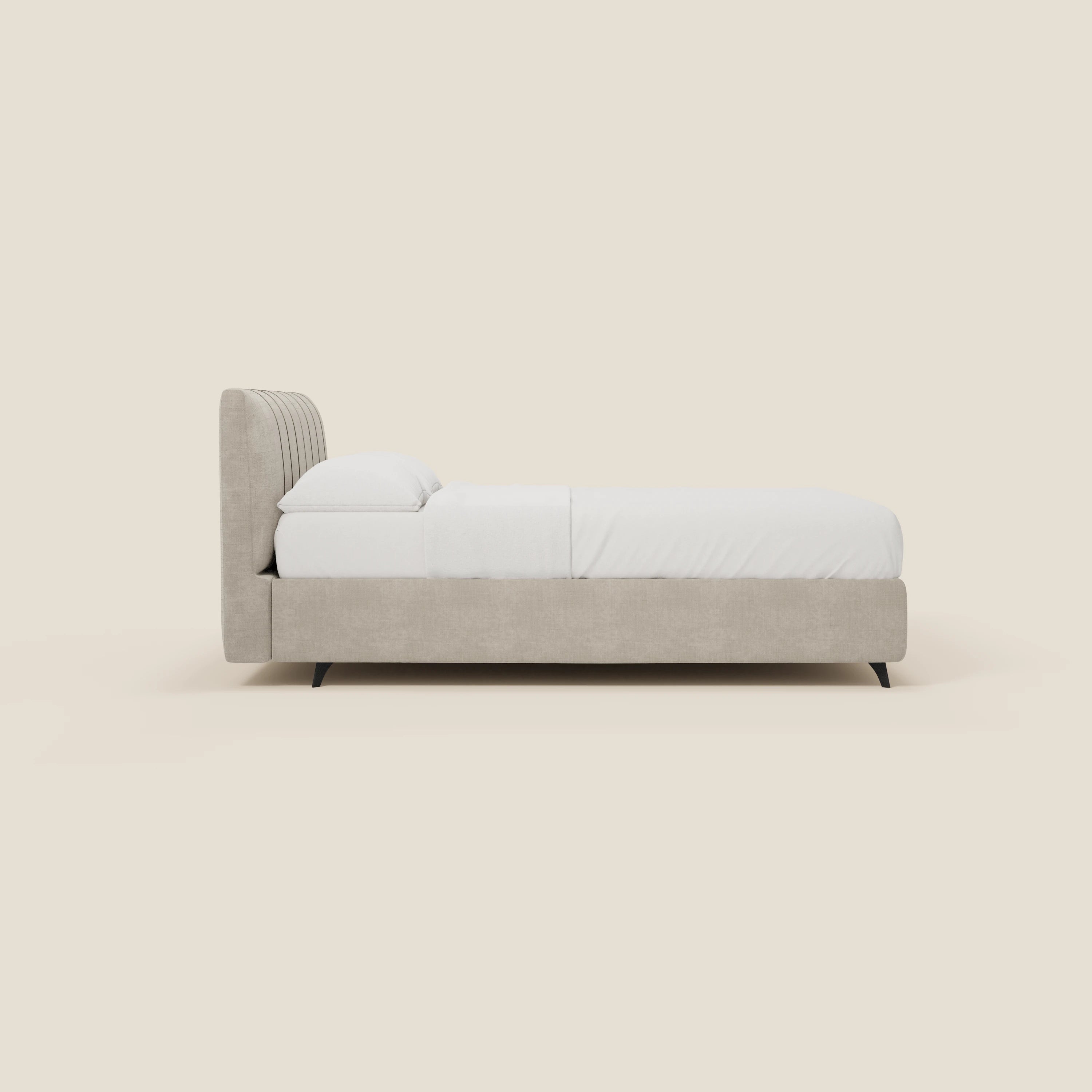 Vista laterale del letto contenitore Bogart Edizione Grande Fratello di Letti.store, in tessuto panna T22 sfoderabile e antimacchia. Testiera alta con cuciture verticali, biancheria da letto bianca, cuscini sovrapposti, gambe corte nere: eleganza italiana minimalista.