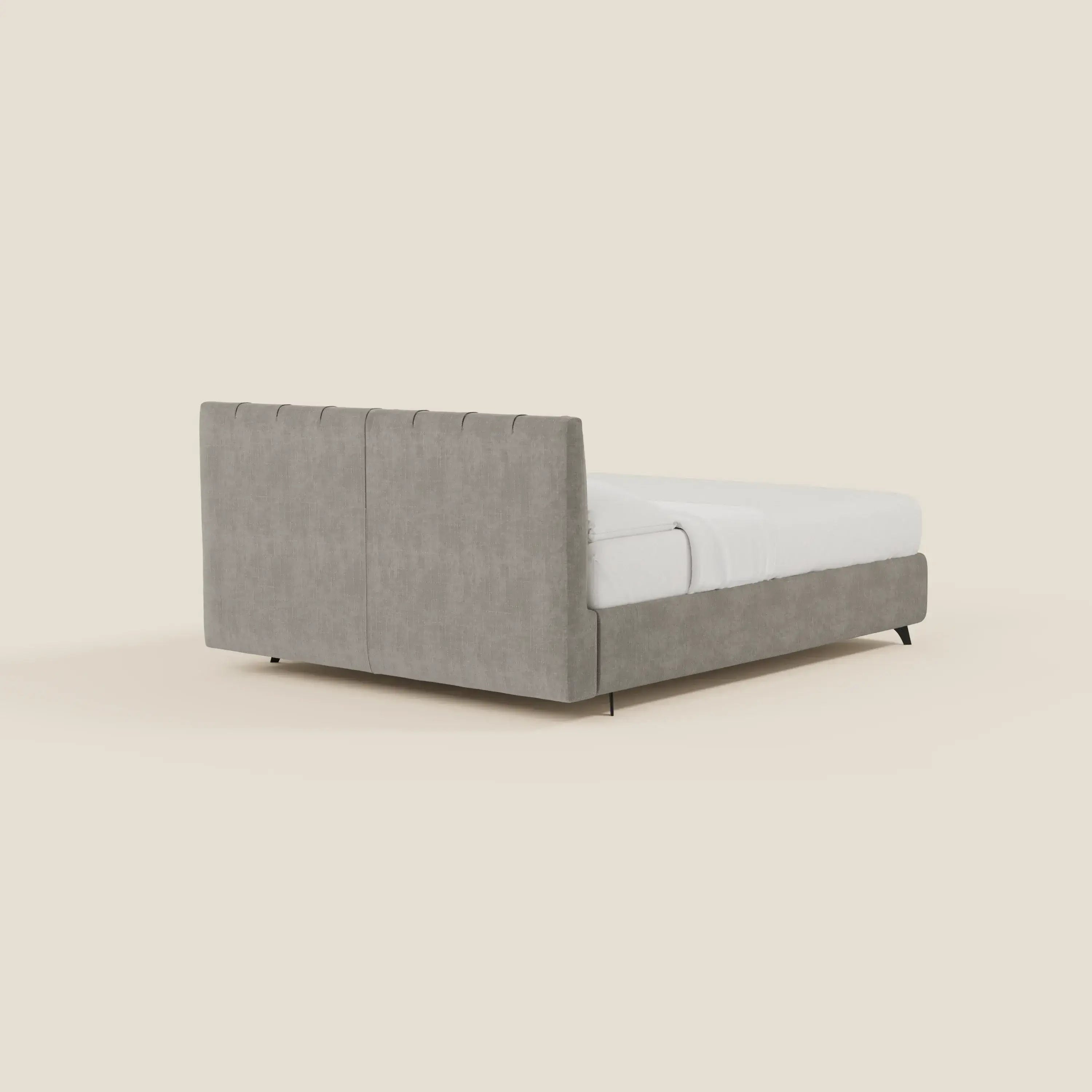 Il letto contenitore Bogart Edizione Grande Fratello di Letti.store è caratterizzato da un rivestimento sfoderabile e antimacchia in tessuto grigio T22 e da una testata imbottita e sottilmente impunturata, visibile dal retro a sinistra su uno sfondo bianco sporco.