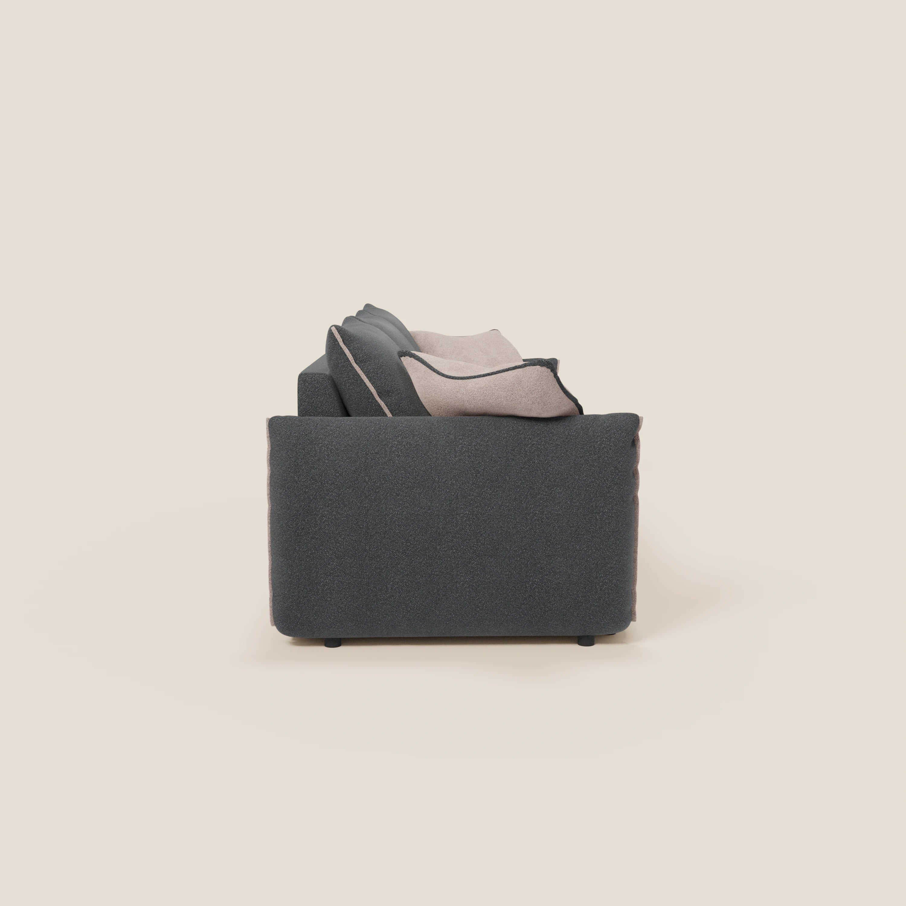 Vista laterale del divano Flexar con 3 sedute allungabili di Divani.Store, in bouclé impermeabile T07 antracite con schienale in piuma d'oca, cuscini beige chiaro e grigio, linee pulite e forma squadrata su fondo beige tinta unita.