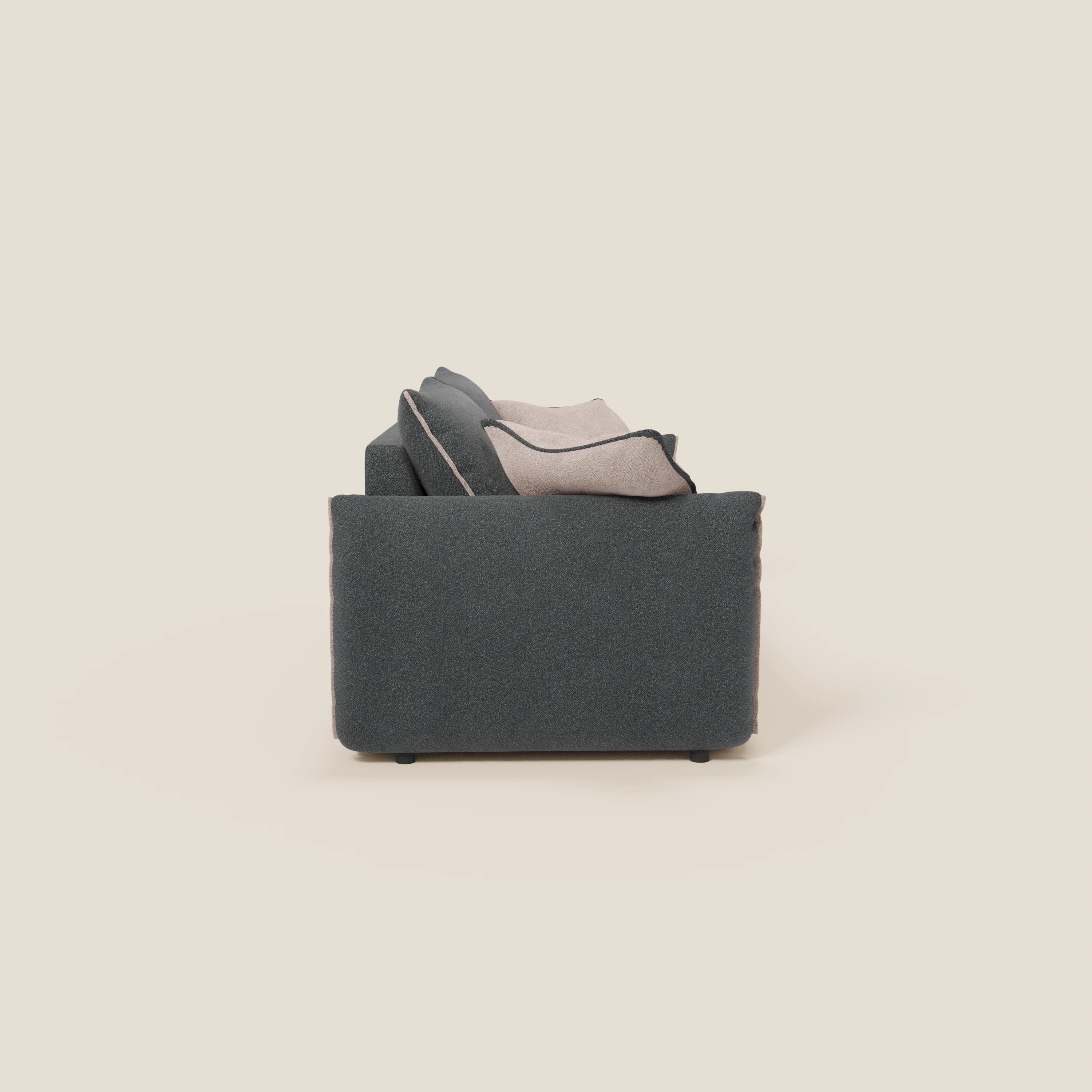 Il divano Flexar con sedute allungabili e schienale in piuma, in morbido bouclé impermeabile T07 antracite-rosa di Divani.Store, è presentato lateralmente su uno sfondo beige chiaro con cuscini di schienale stratificati grigi e beige per un look contemporaneo e accogliente.