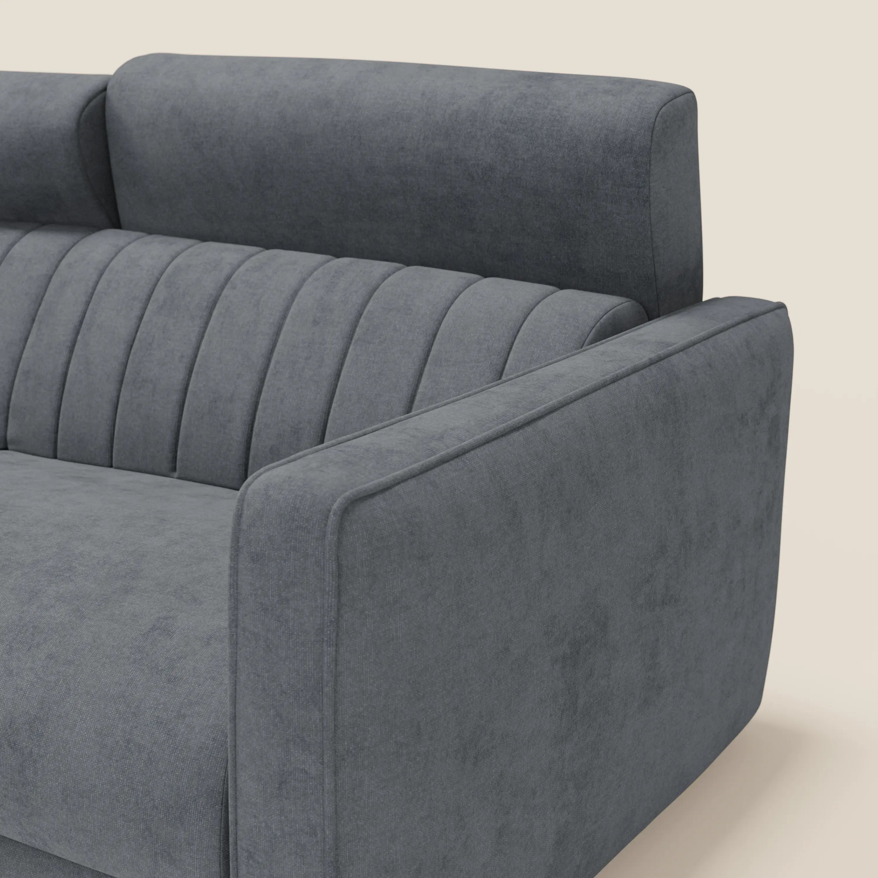 Primo piano di Nivon Divano letto moderno di Divani.Store, rivestito in tessuto impermeabile T25 antracite con ciuffi verticali a canale, ampi braccioli angolari, materasso H16 cm e poggiatesta, su uno sfondo chiaro.