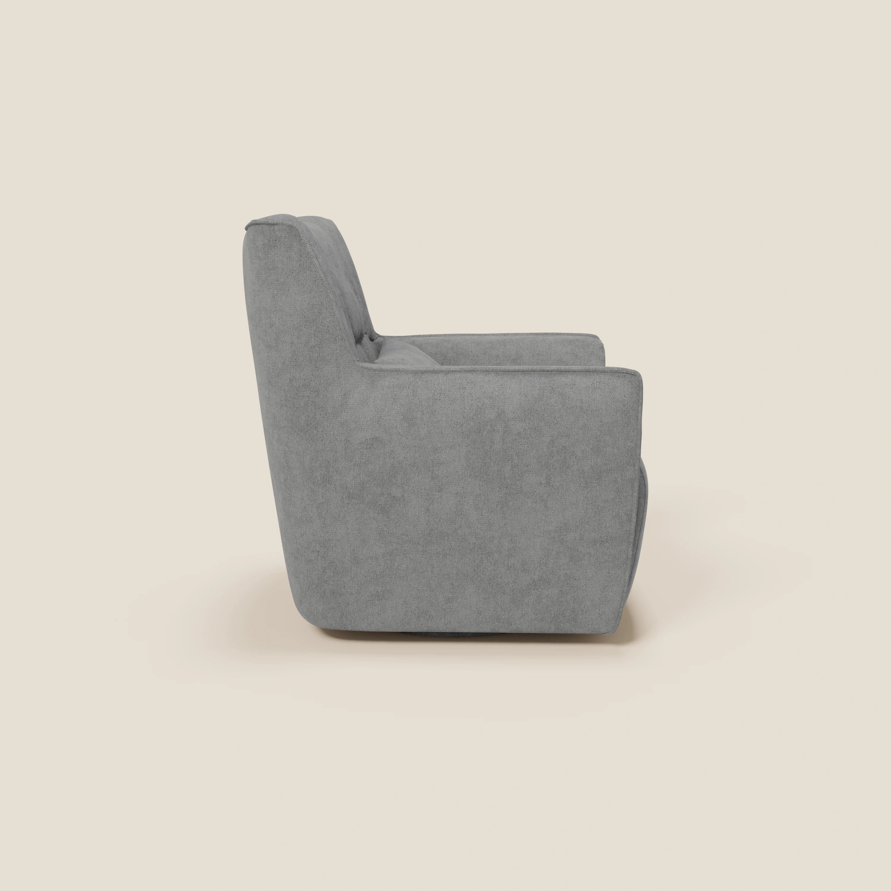 La poltrona girevole Tulla in tessuto impermeabile T02 grigio di Divani.Store è presentata lateralmente su uno sfondo beige chiaro, con cuscini in tessuto, ampi braccioli e un aspetto morbido e squadrato dallo stile minimalista.