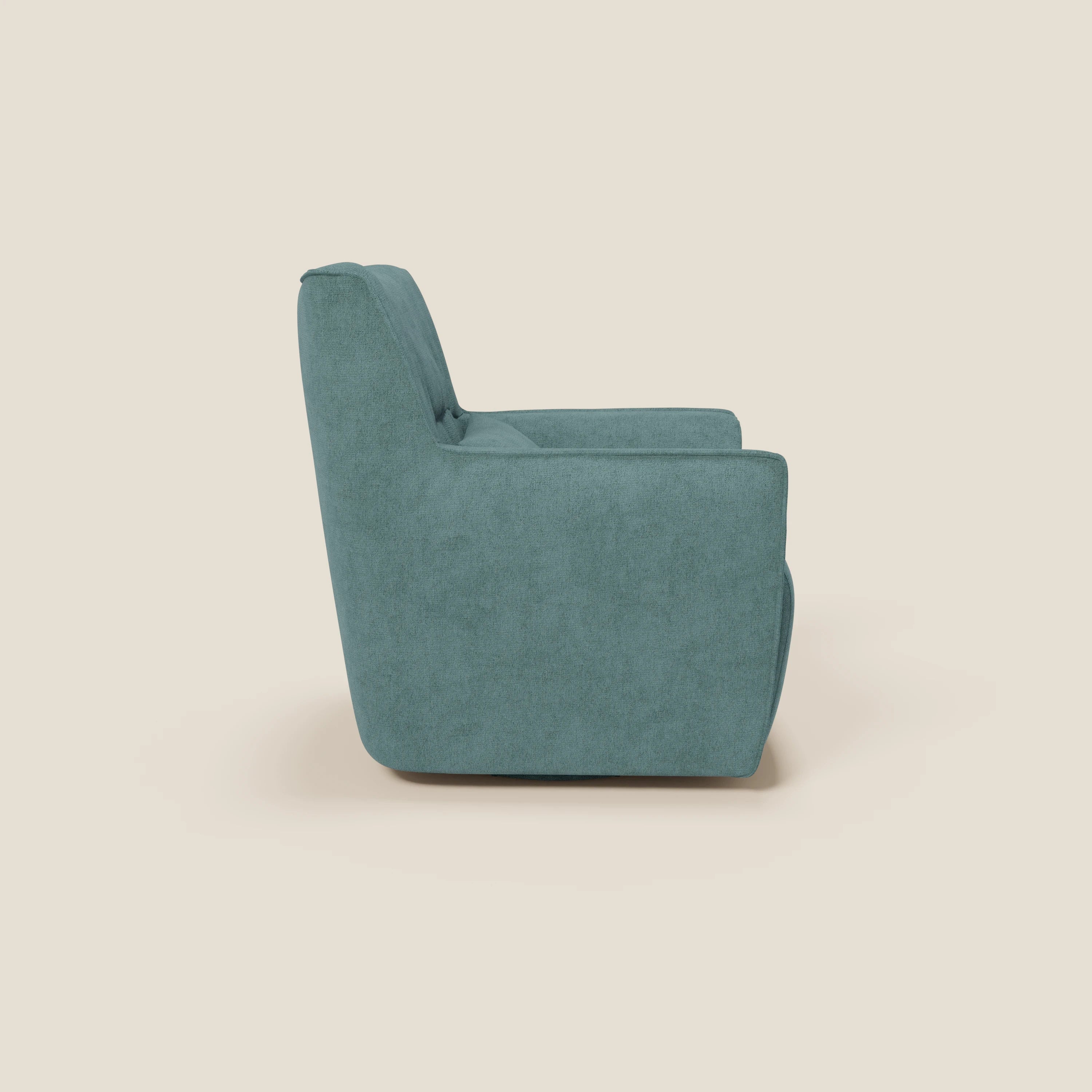 Una vista laterale di Divani.Store Tulla Poltrona girevole in tessuto impermeabile T02 petrolio mostra il suo design moderno e morbido, con lo schienale alto, la spessa seduta imbottita e i braccioli bassi su uno sfondo bianco sporco. Non sono visibili gambe o decorazioni.