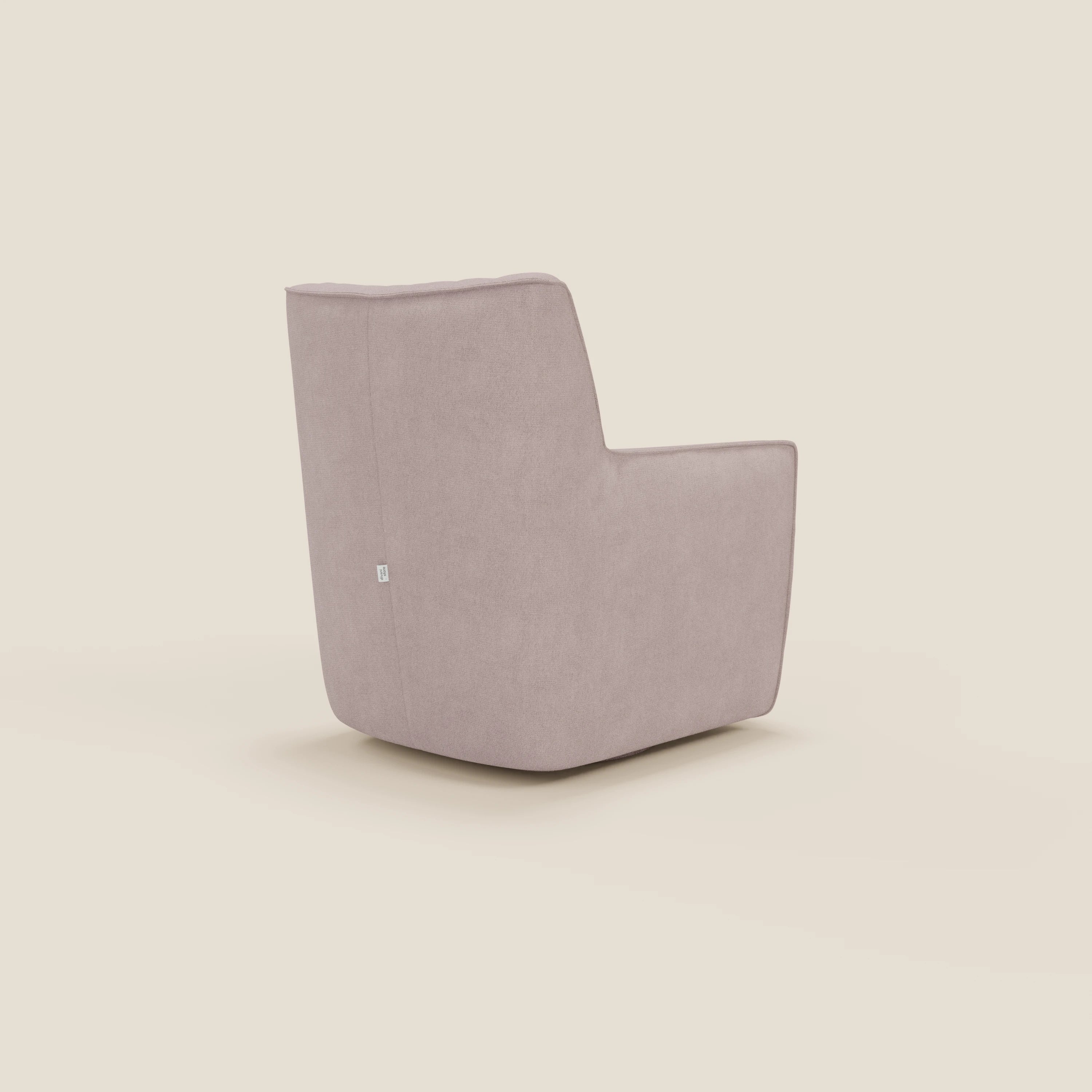 La poltrona girevole Tulla in tessuto impermeabile T02 rosa di Divani.Store, presentata in un angolo posteriore su uno sfondo beige chiaro, è caratterizzata da un'imbottitura in peluche, un design geometrico squadrato con schienale e braccioli alti e una piccola etichetta laterale bianca.