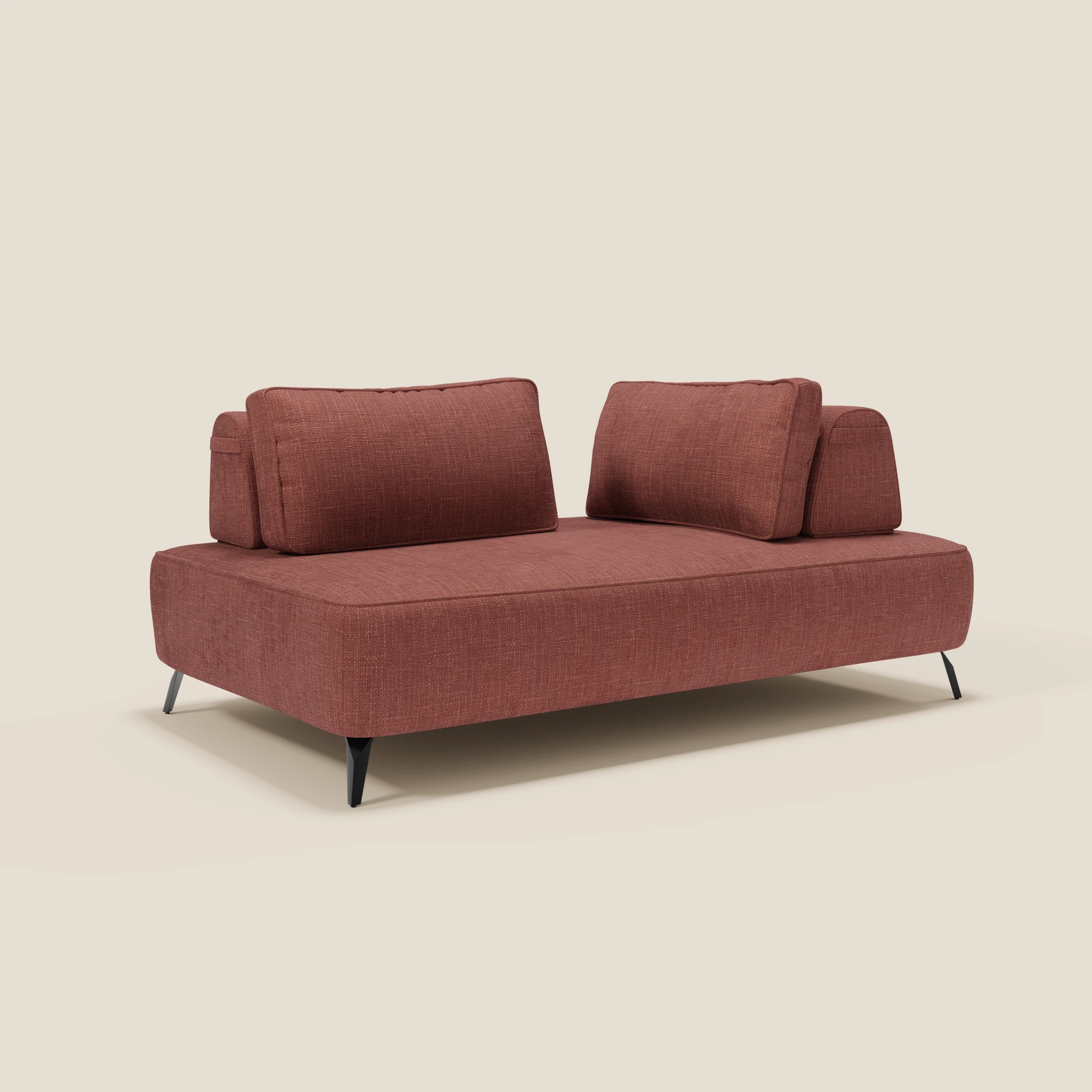 Il divano modulare Volta di Divani.Store, con schienali mobili in ciniglia T06 corallo, due grandi cuscini, braccioli bassi e sottili gambe nere, esprime uno stile contemporaneo su fondo beige chiaro.