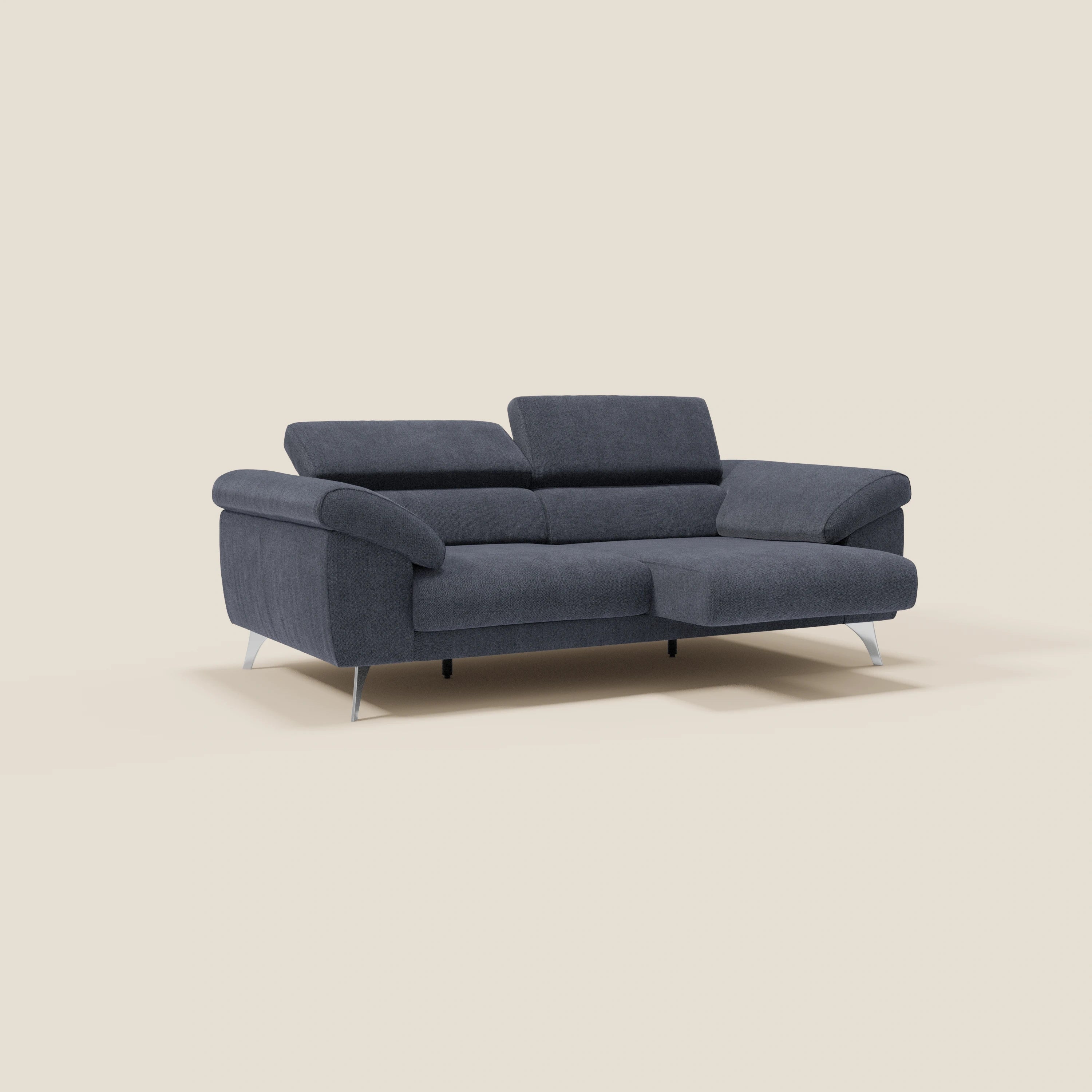 Un divano moderno Donatello di Divani.Store in tessuto smacchiabile T23 blu ardesia, con sedute allungabili, braccioli contenitore e poggiatesta reclinabili, su uno sfondo beige chiaro per un design contemporaneo.