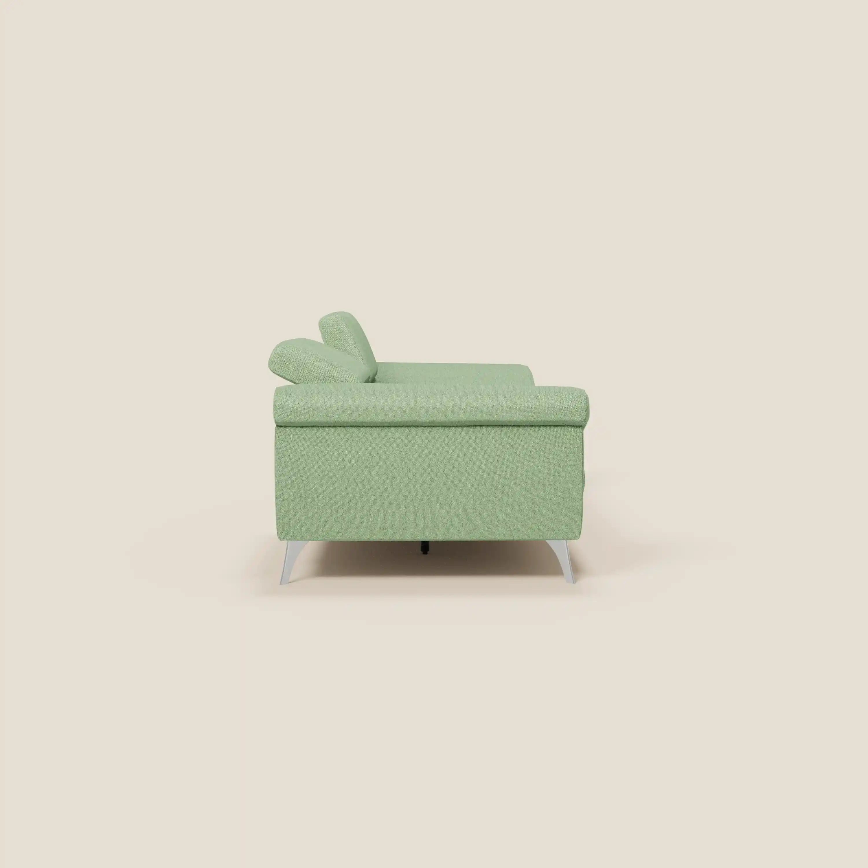 Il divano Donatello con sedute allungabili di Divani.Store in tessuto smacchiabile T23 menta è mostrato di lato su sfondo beige chiaro, con gambe metalliche basse e design minimalista, braccioli contenitore e poggiatesta reclinabili.