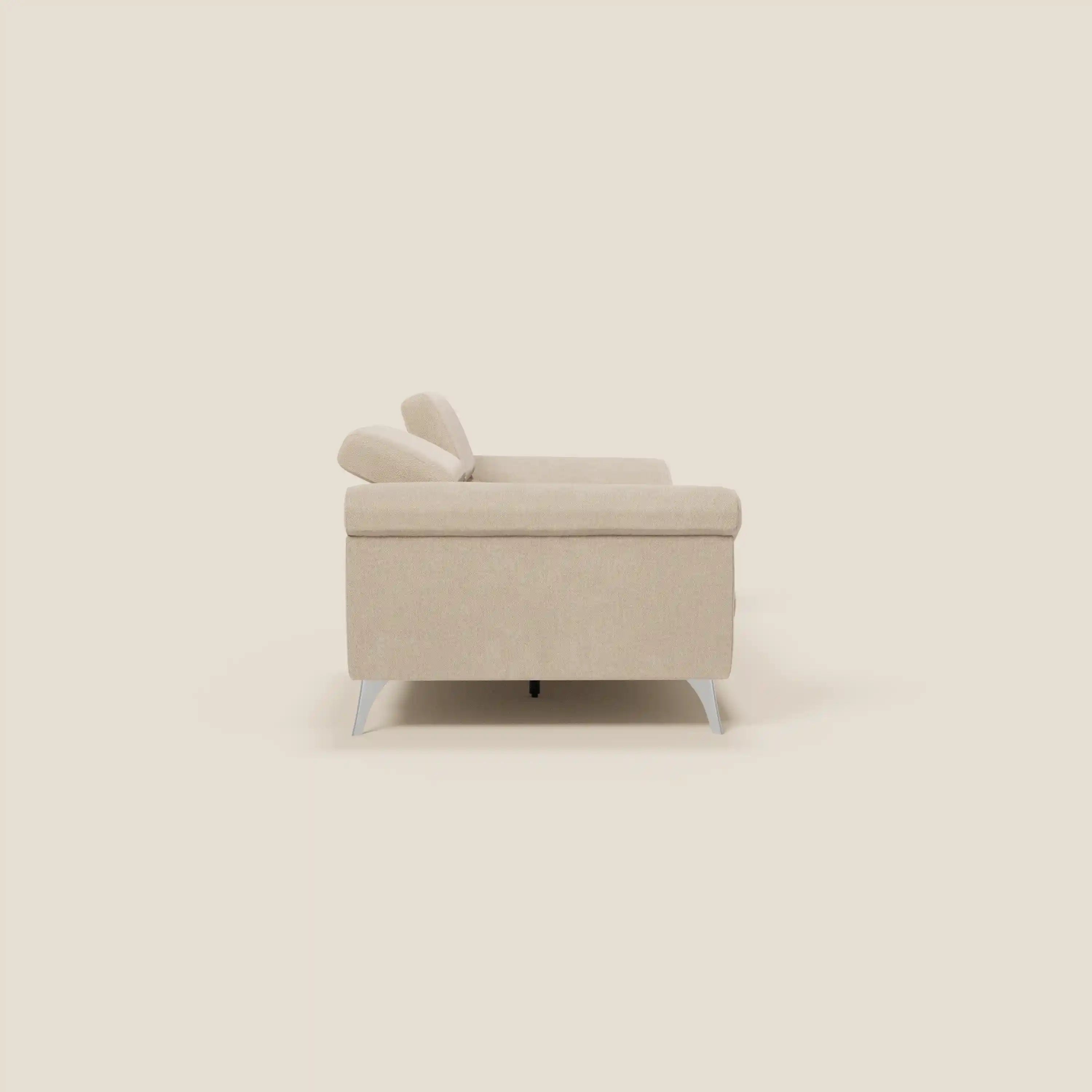 Vista laterale del divano Donatello di Divani.Store in T23 beige, con sedute allungabili, braccioli contenitore e poggiatesta reclinabili; su uno sfondo crema chiaro, spicca il suo design moderno.