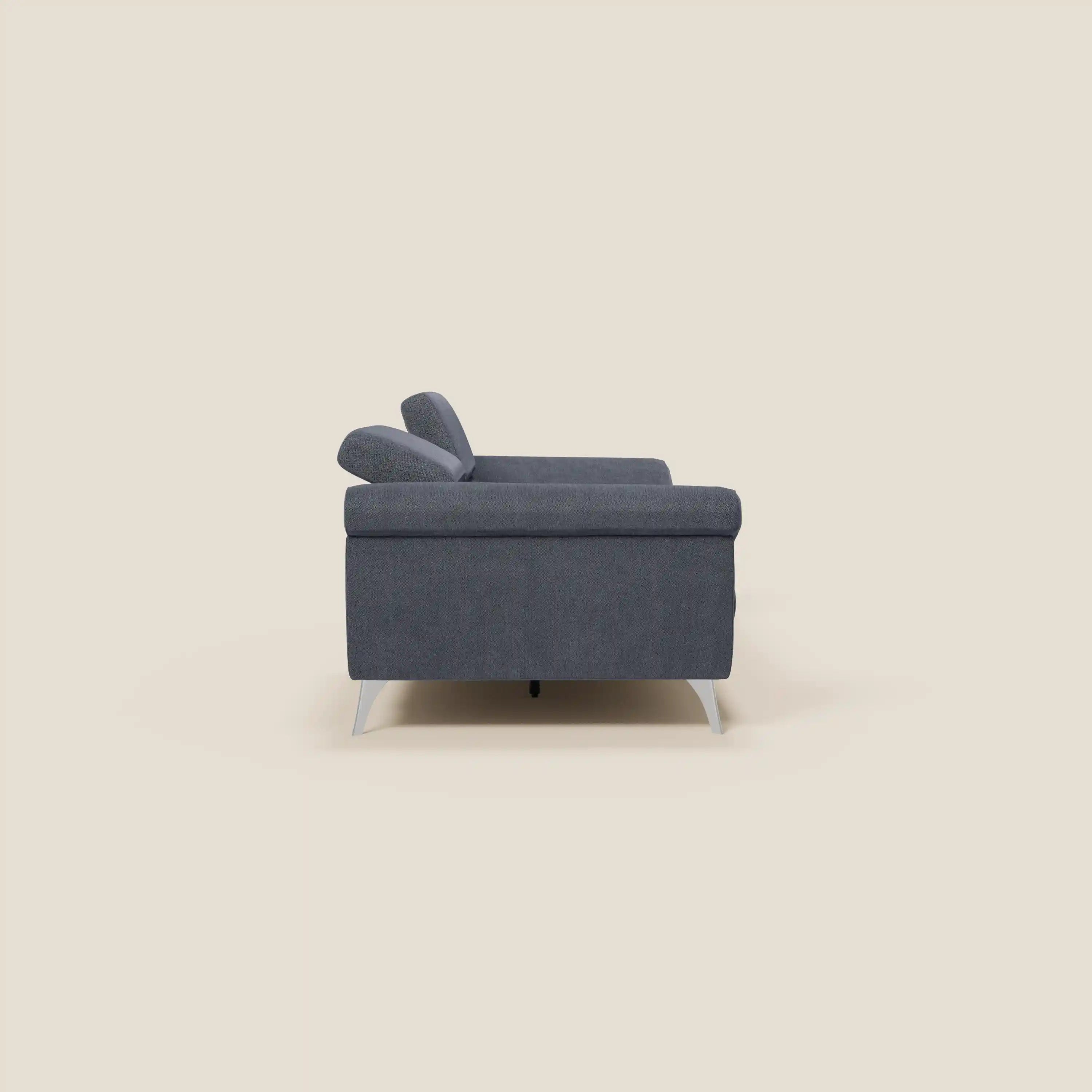 Il divano Donatello con sedute allungabili, braccioli contenitore e poggiatesta reclinabili in tessuto smacchiabile T23 blu ardesia di Divani.Store è mostrato di lato su sfondo beige chiaro, con linee moderne e dettagli funzionali.